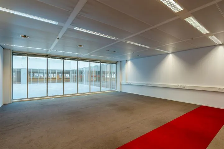 Leeg kantoorruimte aan de Eendrachtlaan met glazen wand en rood tapijtstrook.