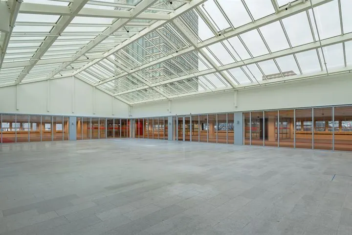 Lichte, ruime hal met glazen dak en glazen wanden aan de Eendrachtlaan.