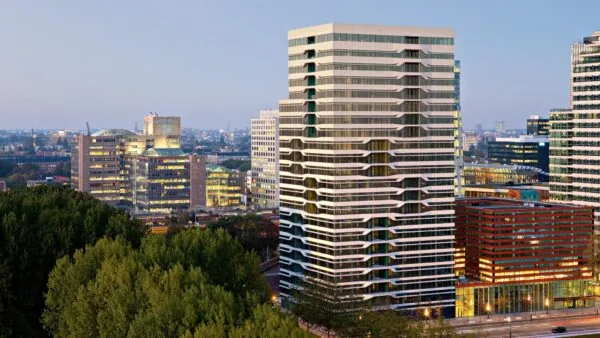Moderne kantoorgebouwen aan de Parnassusweg in Amsterdam bij schemerlicht, met uitzicht op de stad en omliggend groen.