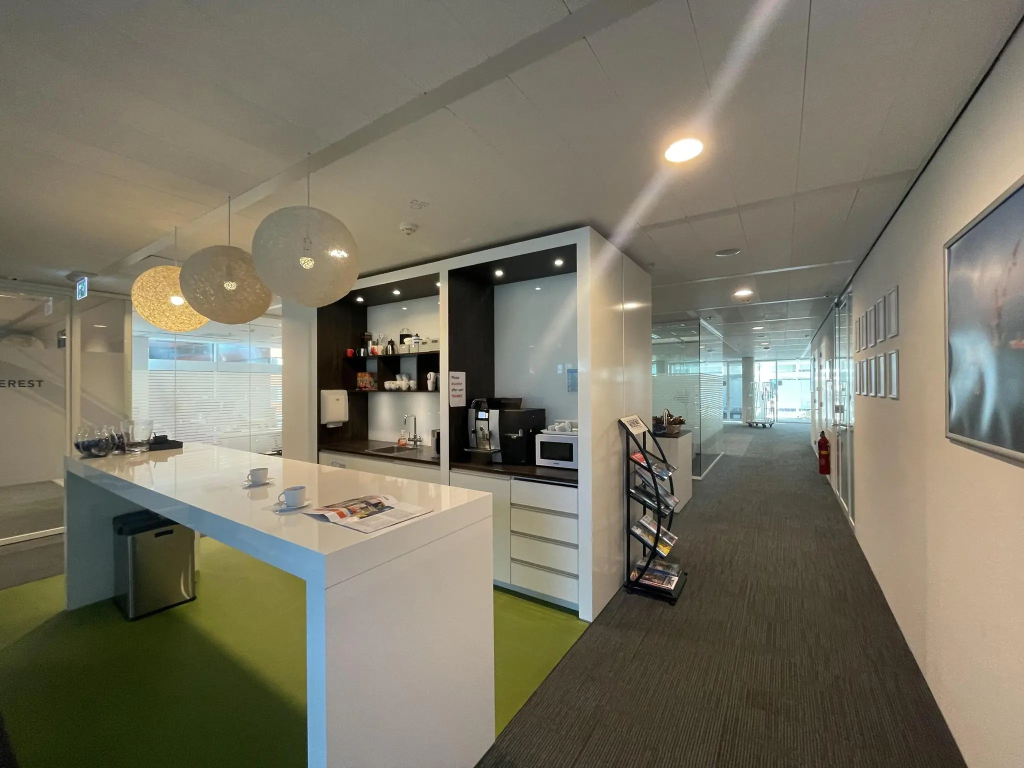 Moderne kantoorpantry aan de Parnassusweg met koffiehoek, zitgedeelte en tijdschriftenrek.