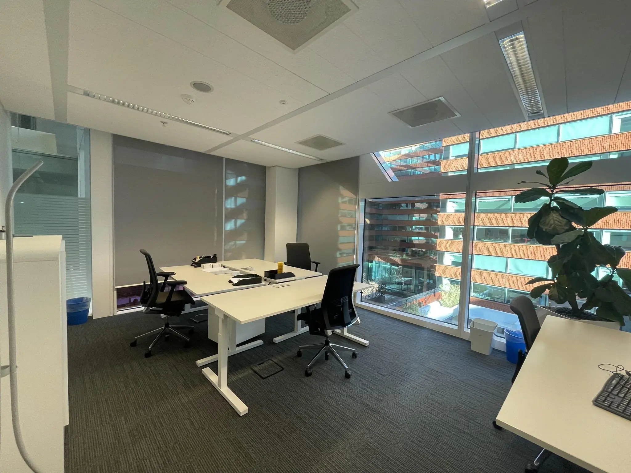 Modern kantoor met bureaus en stoelen aan de Parnassusweg, met uitzicht op een gebouw met roodstenen gevel en grote ramen.