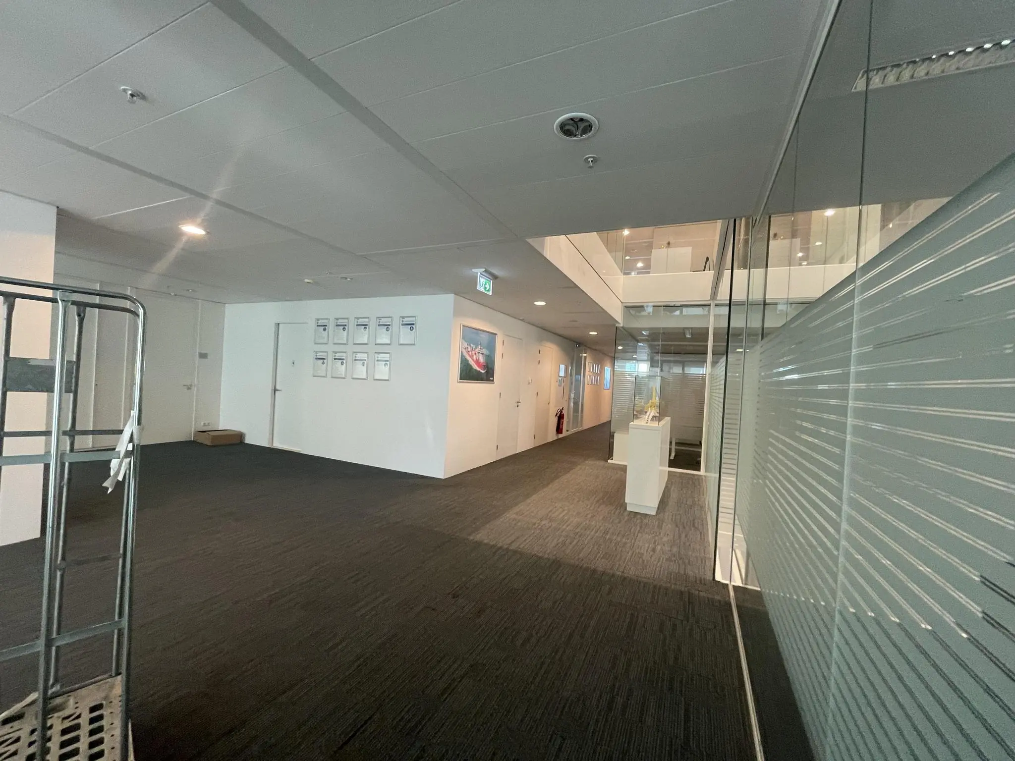 Moderne kantoorhal in het Parnassusweg-gebouw met glazen wand, kunstwerken en certificaten aan de muur.