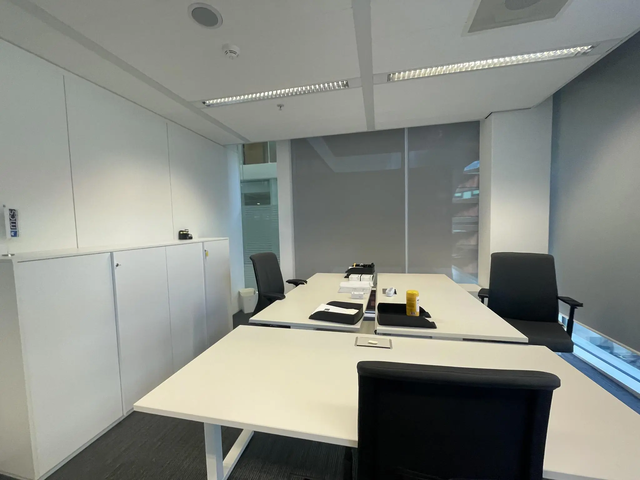 Moderne vergaderruimte aan de Parnassusweg met witte tafels, zwarte stoelen en gesloten jaloezieën.
