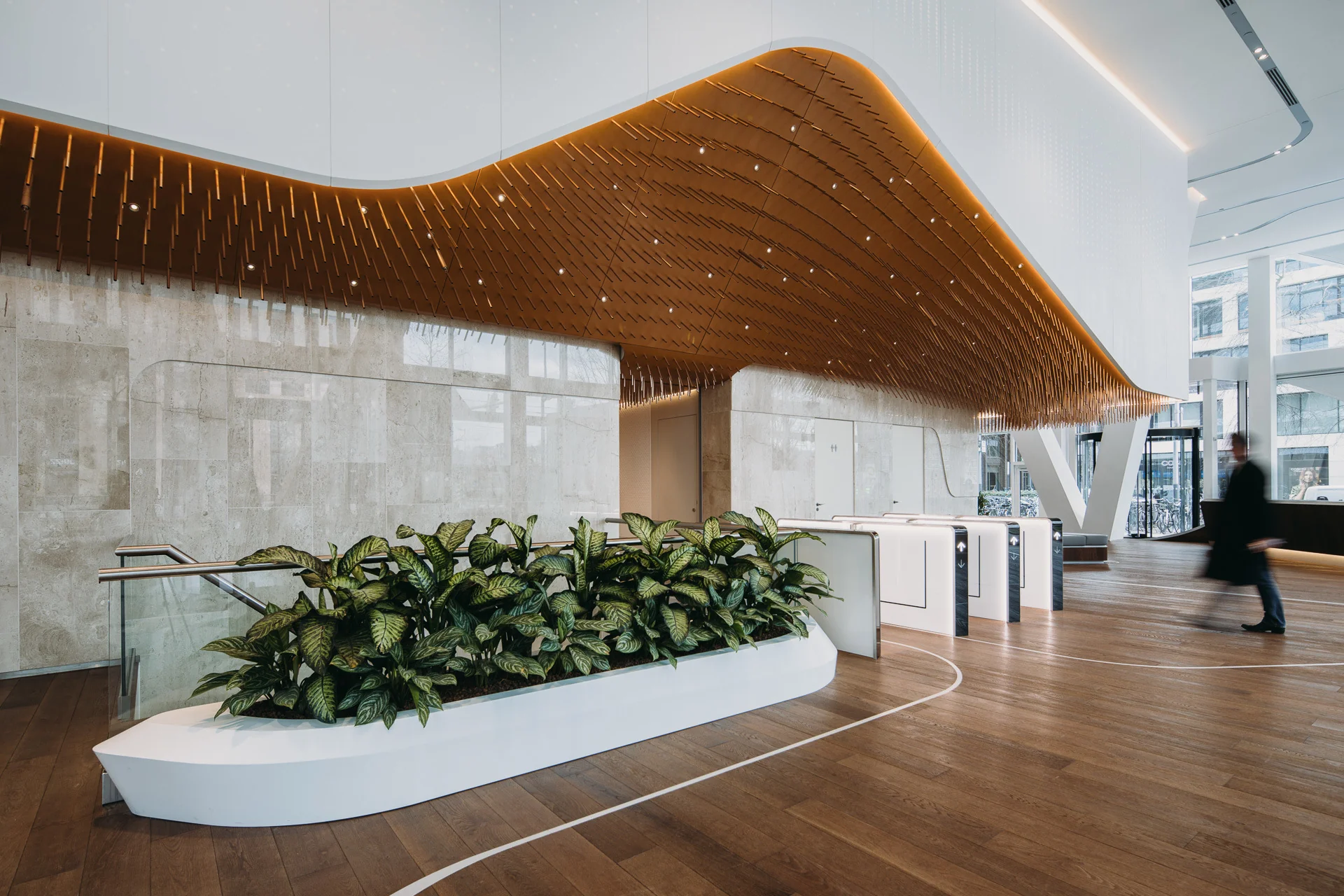 Moderne entreehal van een kantoorgebouw aan de Parnassusweg met houten vloer, plafond met houten lamellen en een plantenbak als afscheiding.