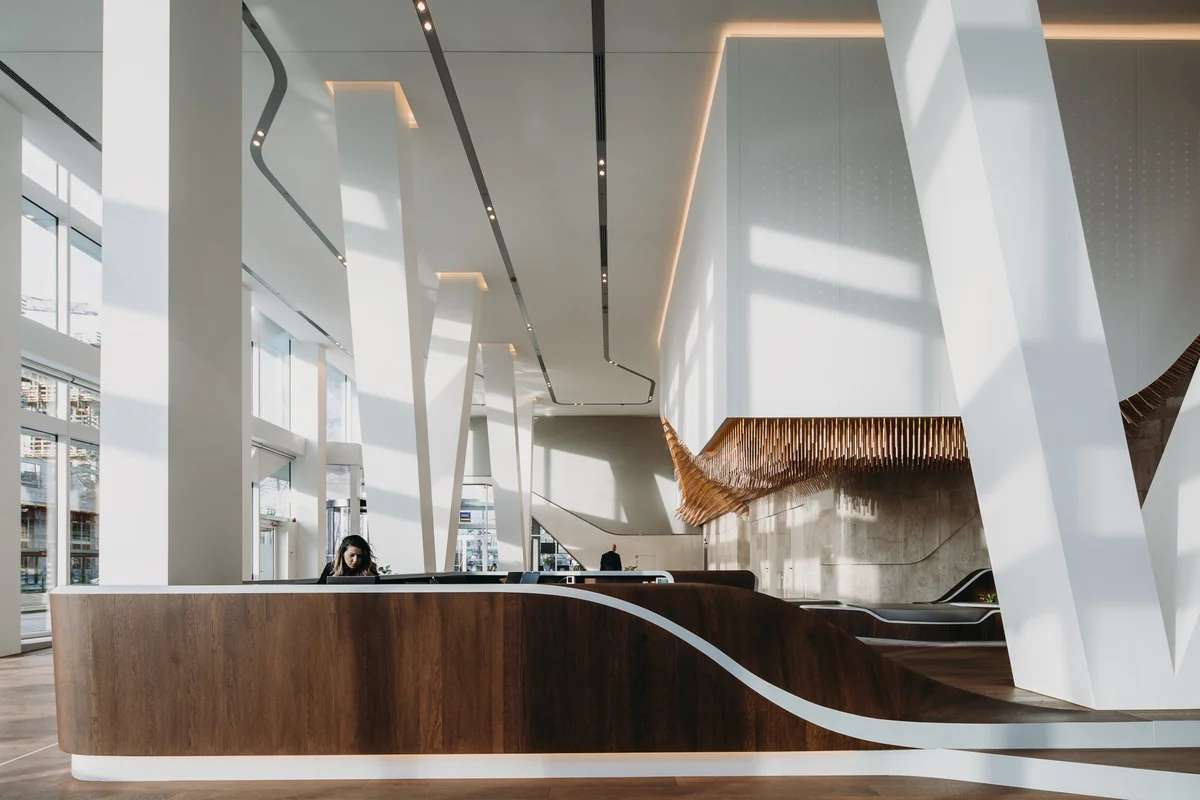 Moderne en lichte entreehal van een kantoorgebouw aan de Parnassusweg met houten receptiebalie en opvallende architectonische elementen.