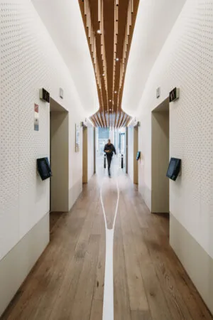 Moderne liftlobby aan de Parnassusweg met houten vloer, strak wit design en houten plafondaccenten.