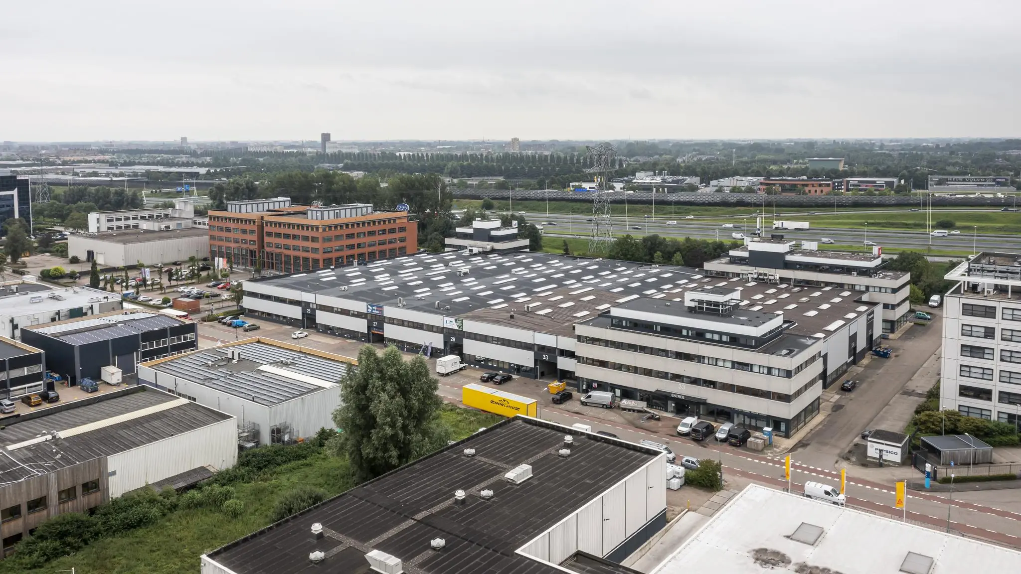Luchtfoto van bedrijventerrein aan de Zonnebaan in Utrecht met kantoren, bedrijfsgebouwen en snelweg op de achtergrond.
