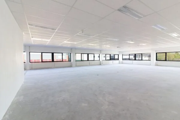 Leeg, licht kantoorruimte met systeemplafond en grote ramen aan de Zonnebaan.