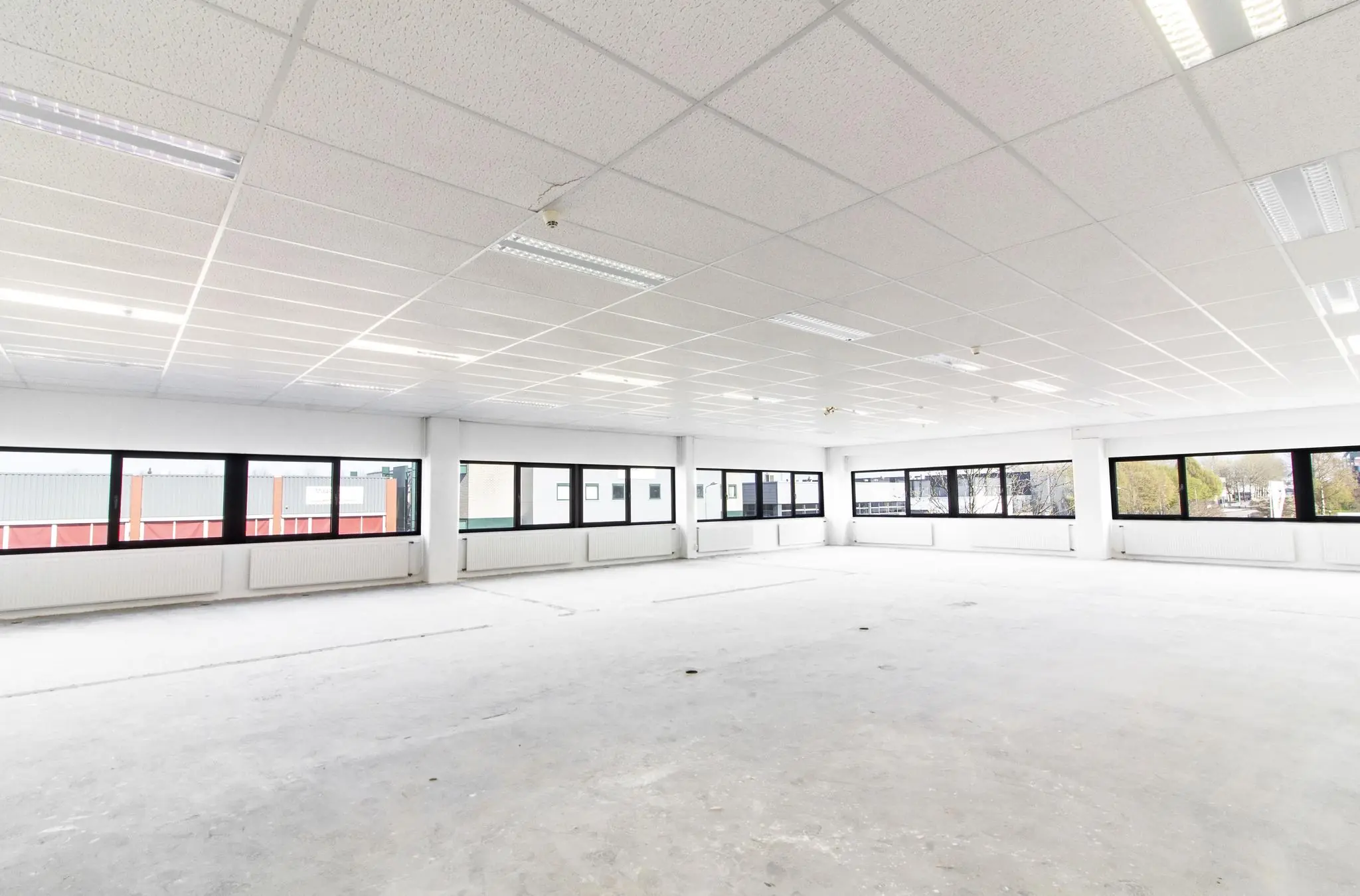Licht en leeg kantoorruimte met systeemplafond en grote ramen aan de Zonnebaan.
