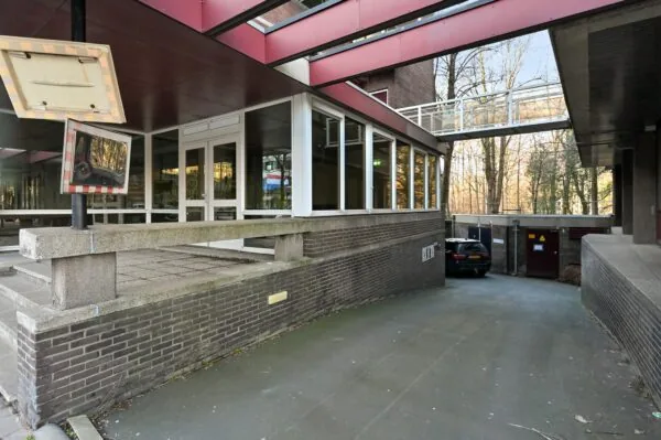 Ingang van een kantoorgebouw aan de Bezuidenhoutseweg met oprit naar ondergrondse parkeergarage en spiegel voor uitrijdend verkeer.