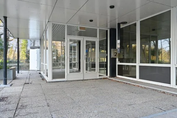 Ingang van een modern kantoorpand aan de Bezuidenhoutseweg met glazen deuren en betonnen terras.