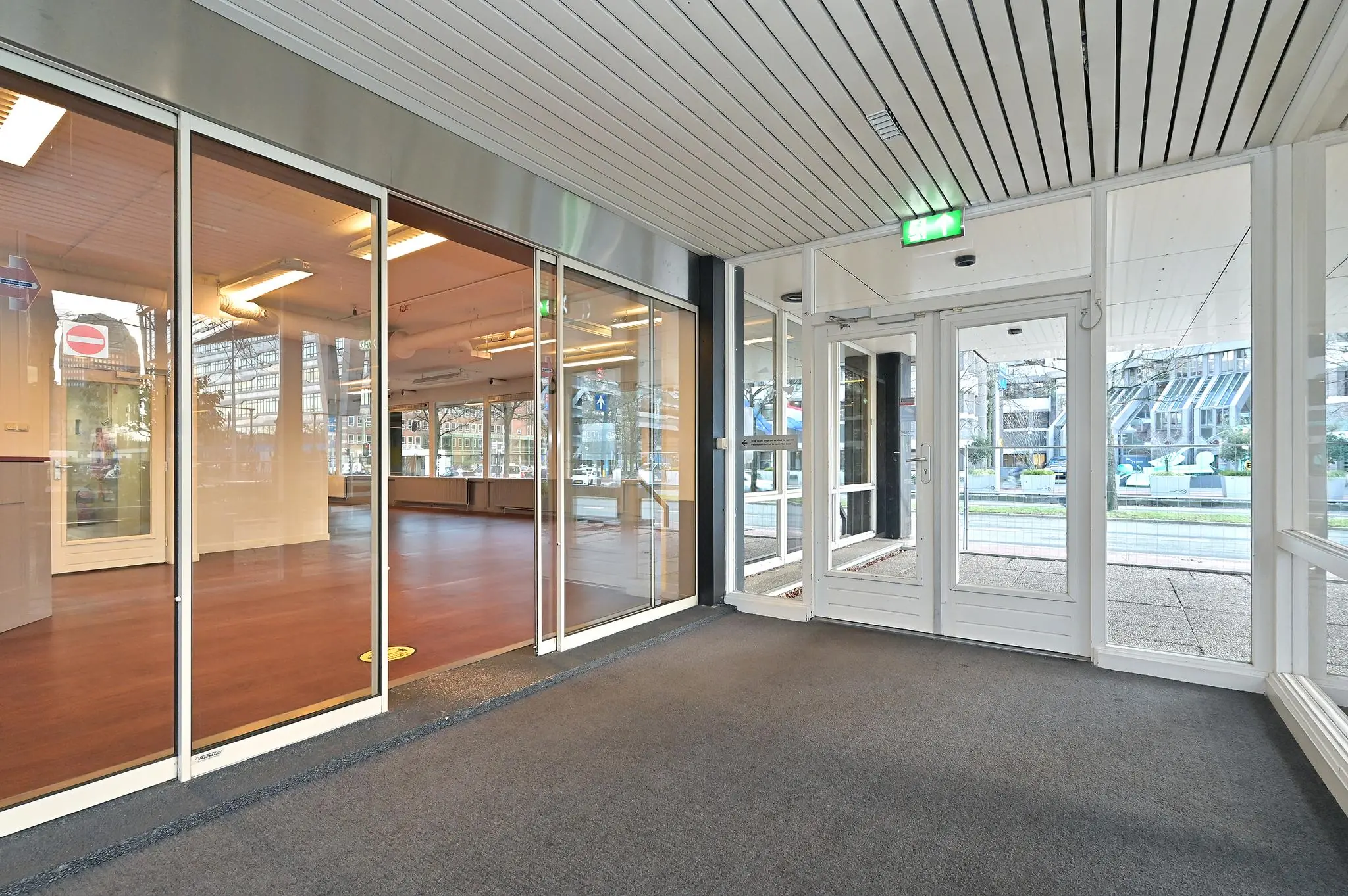 Entreehal met glazen wanden en uitzicht op Bezuidenhoutseweg in Den Haag.