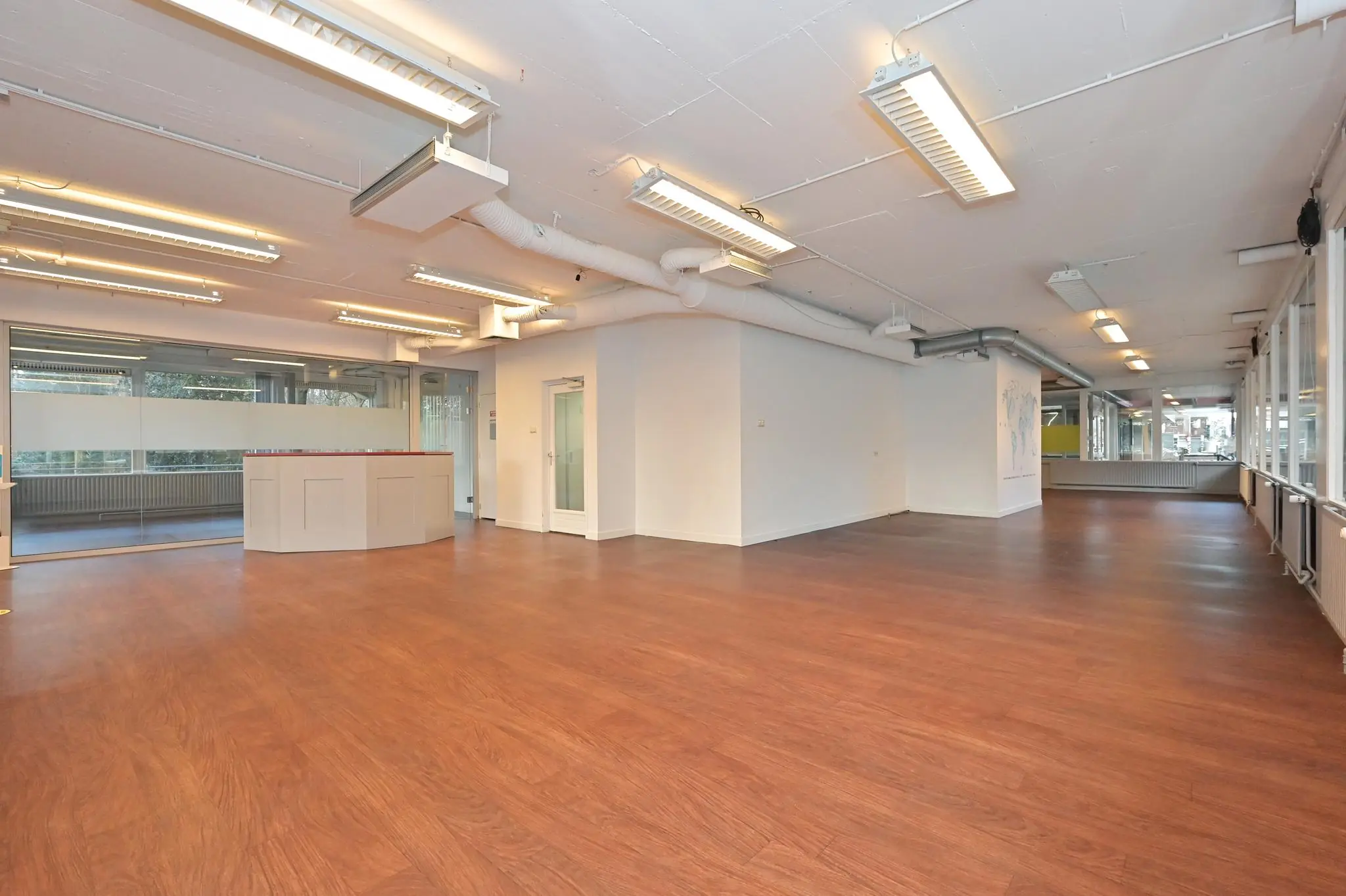 Ruime, moderne kantoorruimte aan de Bezuidenhoutseweg met houten vloer en grote ramen.
