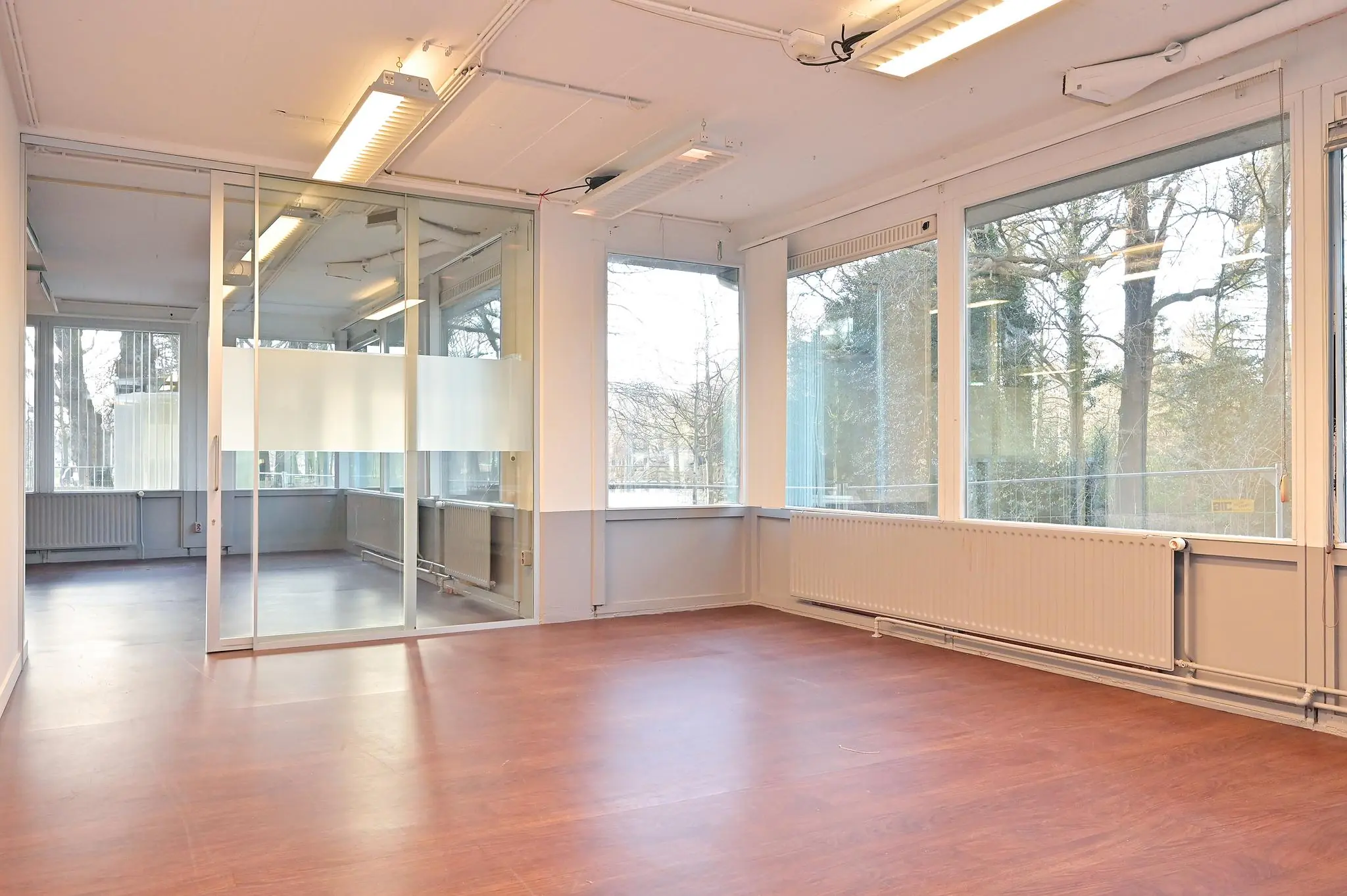 Licht en modern kantoorpand aan de Bezuidenhoutseweg met grote ramen en glazen scheidingswand.