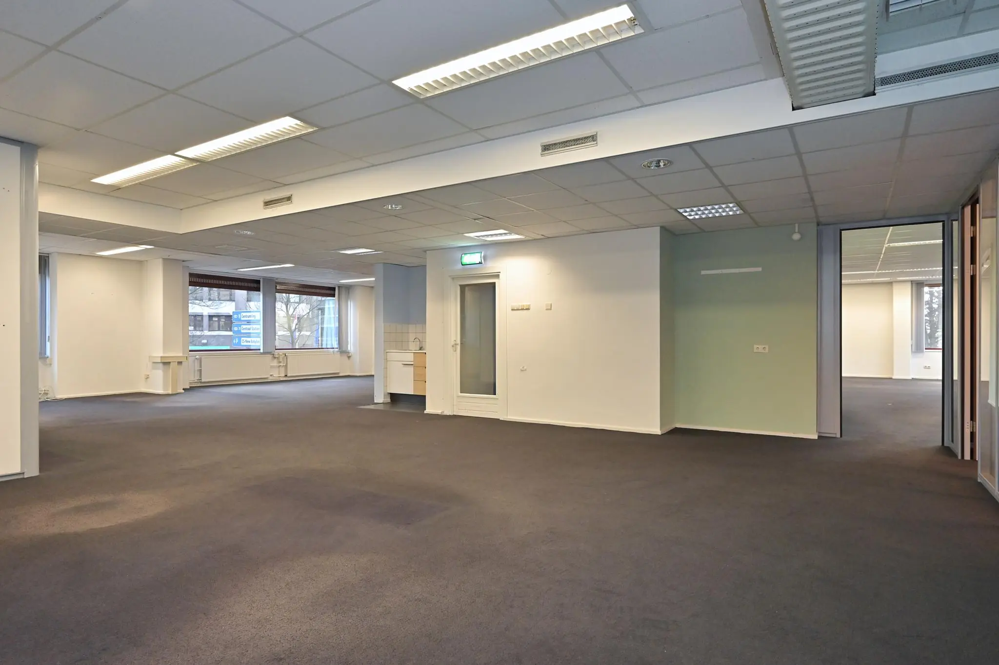 Lichte, leegstaande kantoorruimte aan de Bezuidenhoutseweg met systeemplafond en grote ramen.