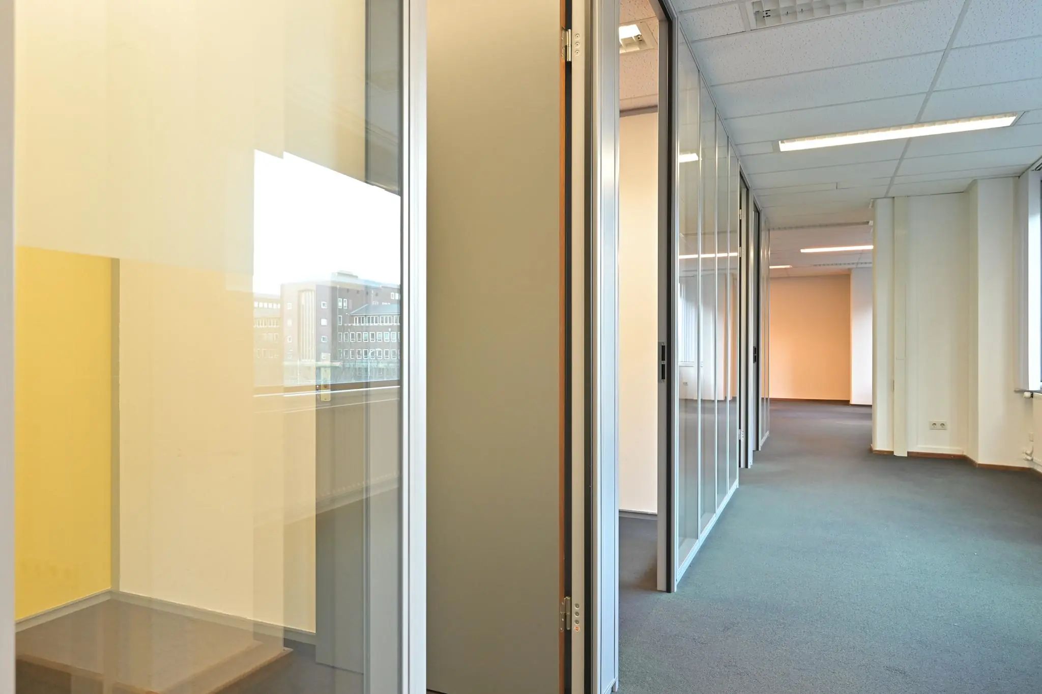 Moderne kantoorruimte aan de Bezuidenhoutseweg met glazen wanden en systeemplafond.