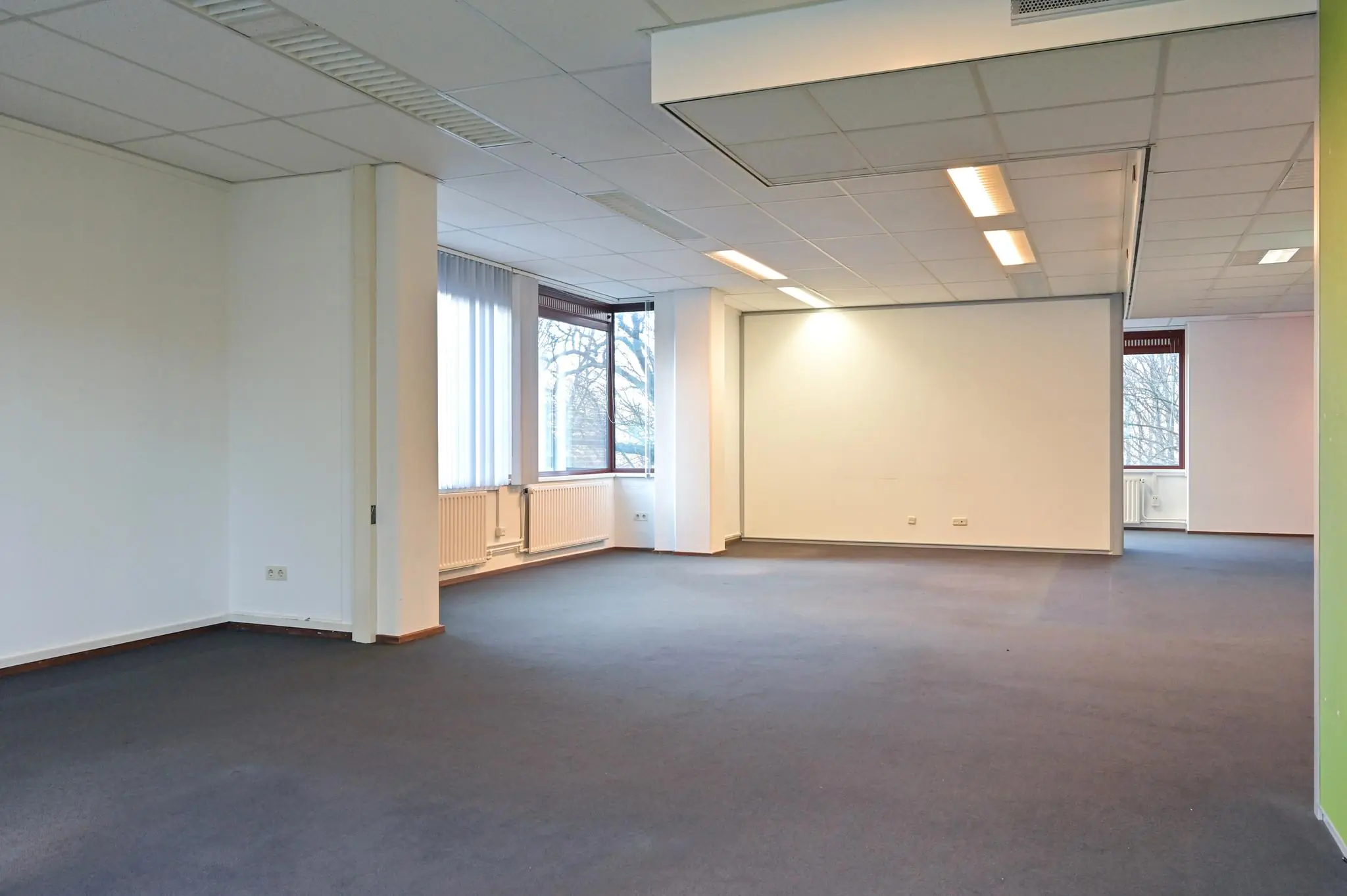 Leeg kantoorruimte aan de Bezuidenhoutseweg met grote ramen en systeemplafonds.