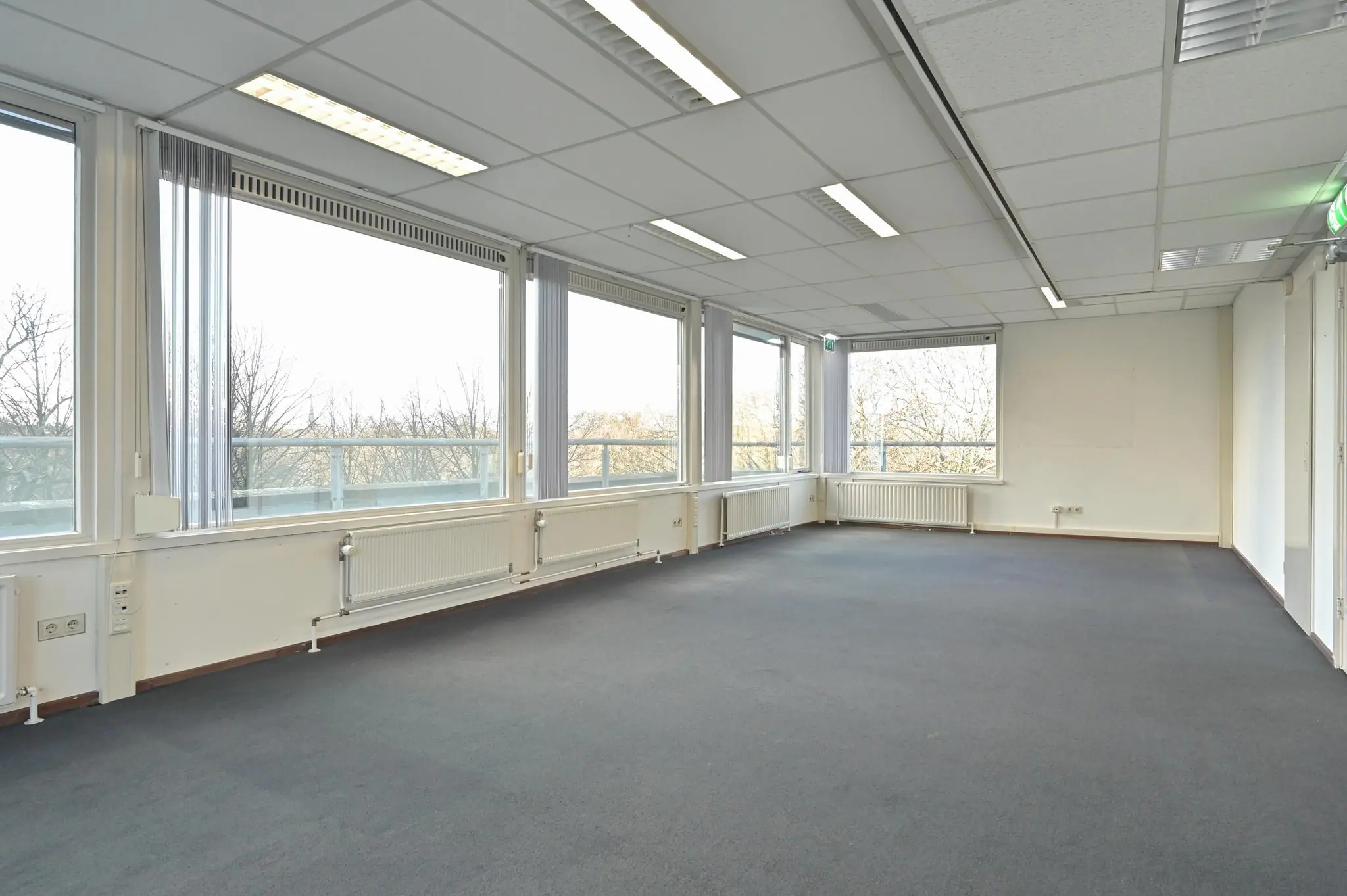 Lichte, lege kantoorruimte aan de Bezuidenhoutseweg met grote ramen en systeemplafond.