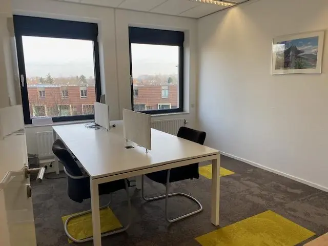 Kleine, moderne kantoorruimte aan de Oudlaan met twee werkplekken en uitzicht op een woonwijk.