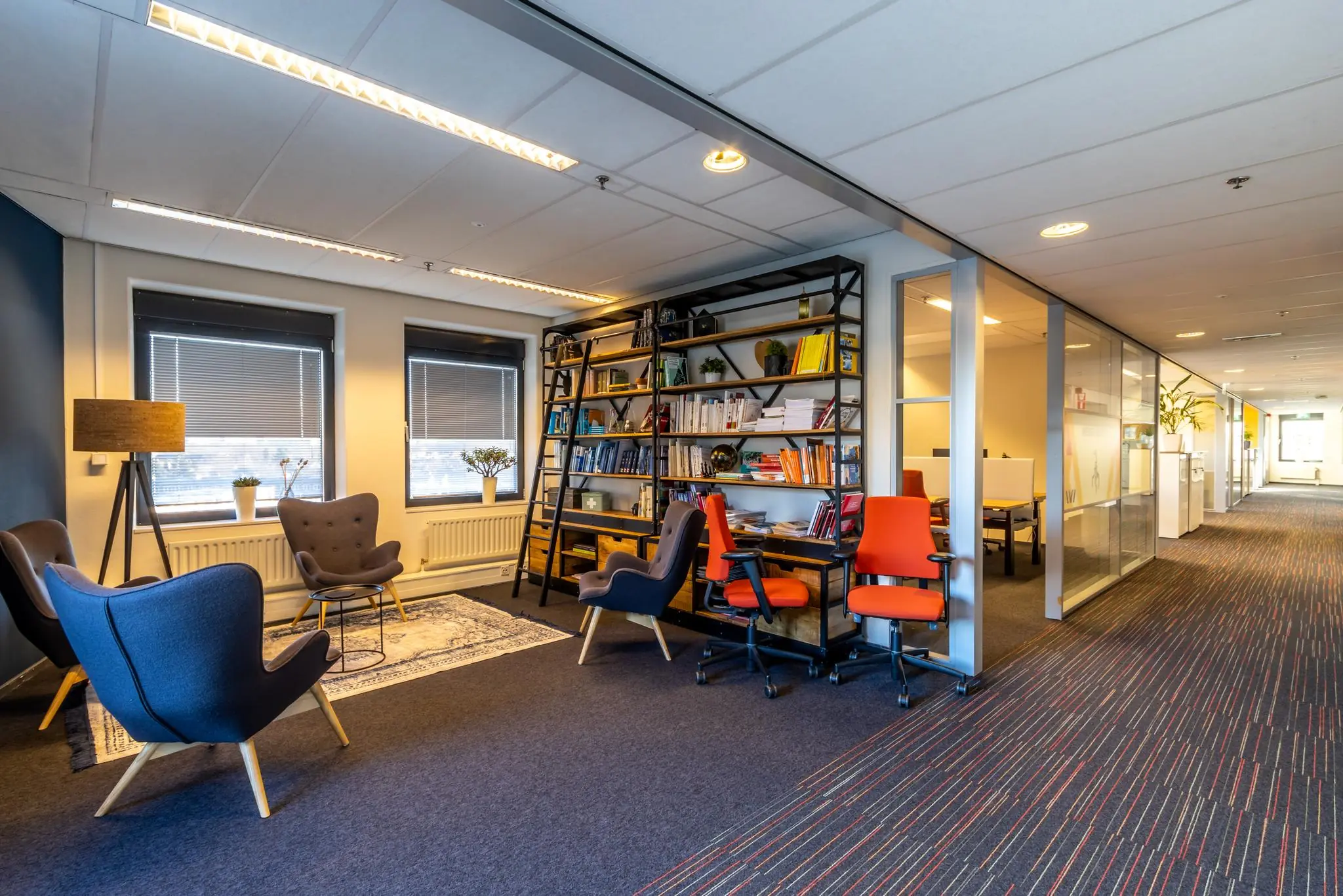 Moderne kantoorruimte aan de Oudlaan met loungehoek, boekenkast en glazen vergaderruimtes.