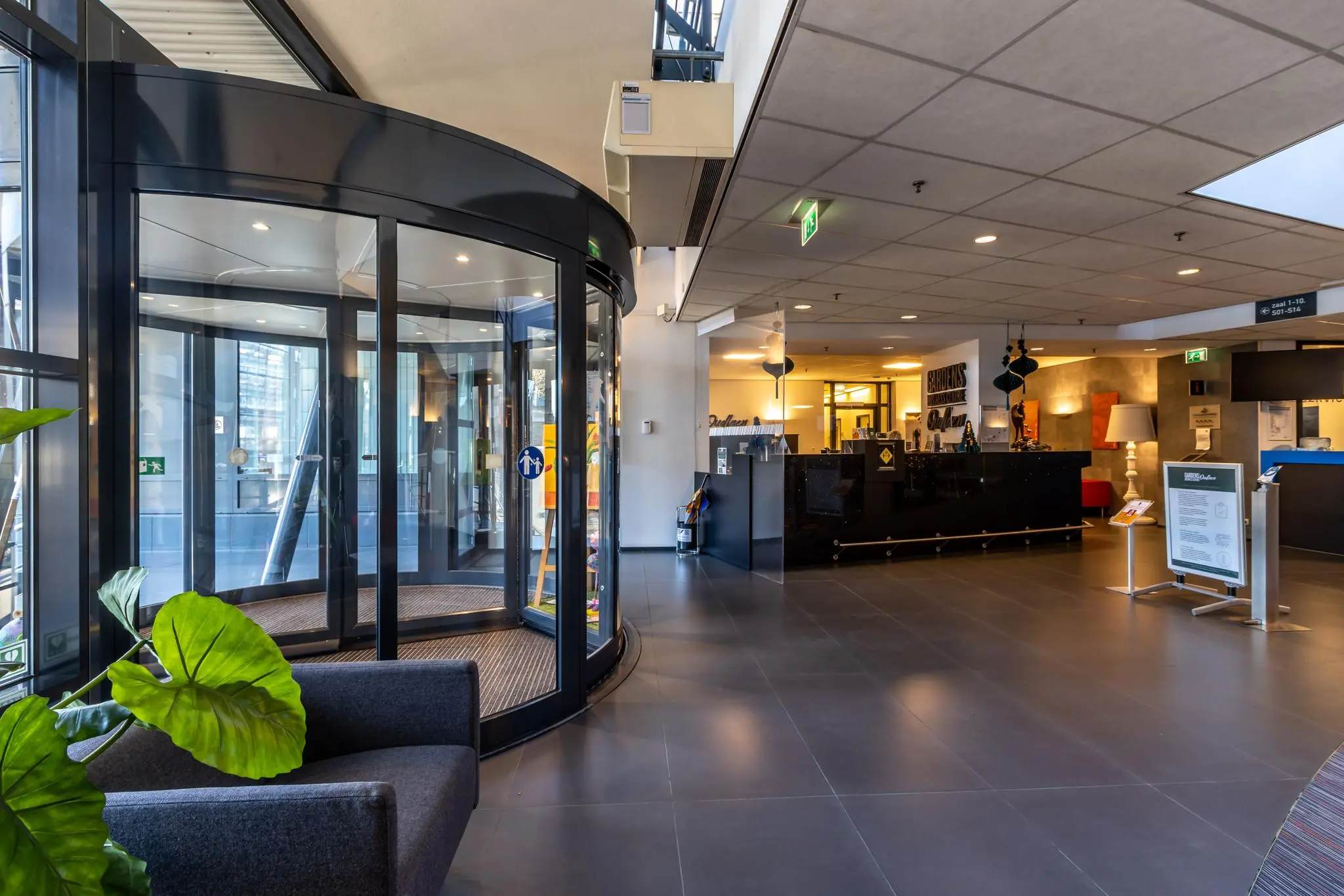 Ingang van een modern kantoorgebouw aan de Oudlaan met een draaideur en receptiebalie.