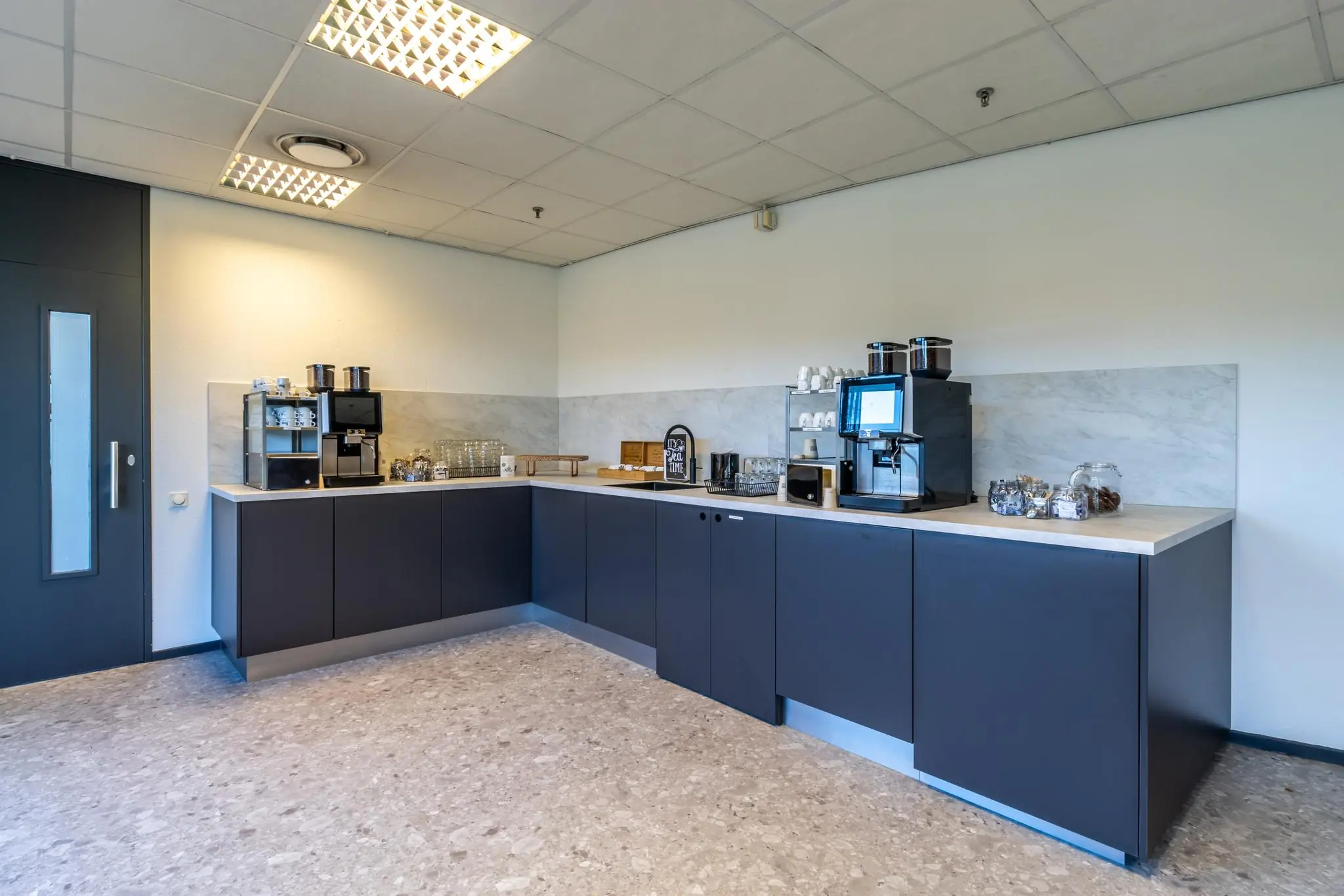 Moderne koffiehoek met meerdere koffiemachines, kopjes, glazen en snacks op Oudlaan 139.