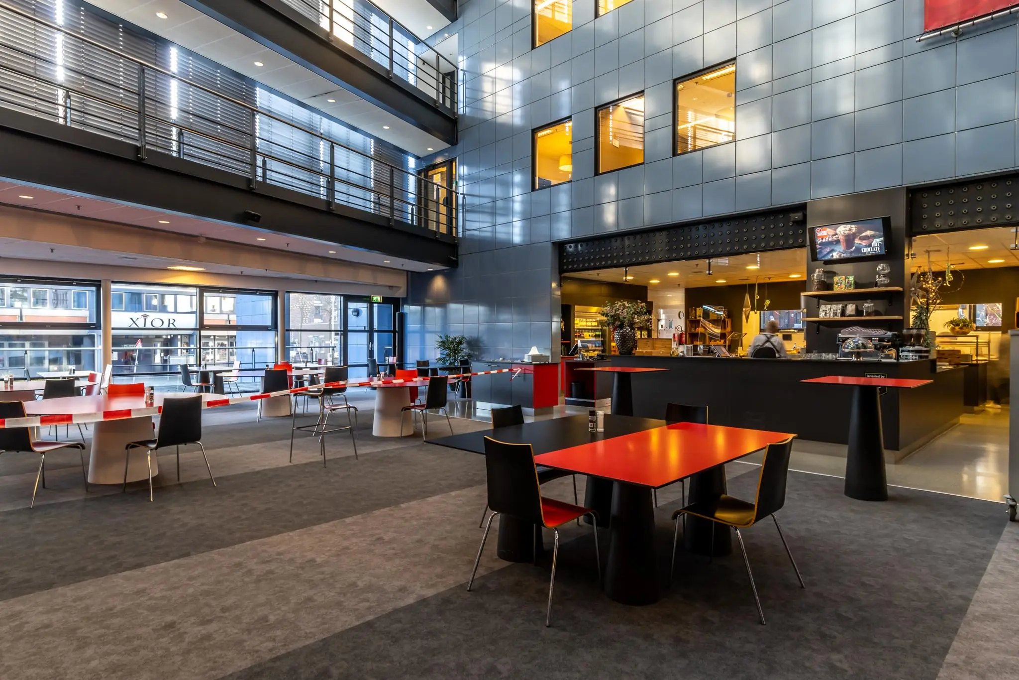 Moderne en ruime kantine met rood-zwarte tafels in een gebouw aan de Oudlaan.