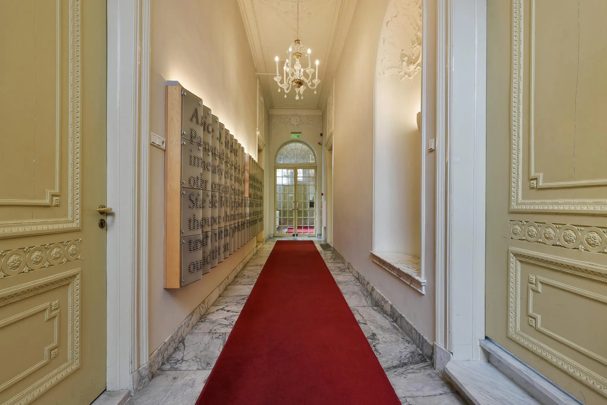Luxe gang in een monumentaal pand aan het Rapenburg met een rode loper, marmeren vloer en sierlijke plafonddetails.