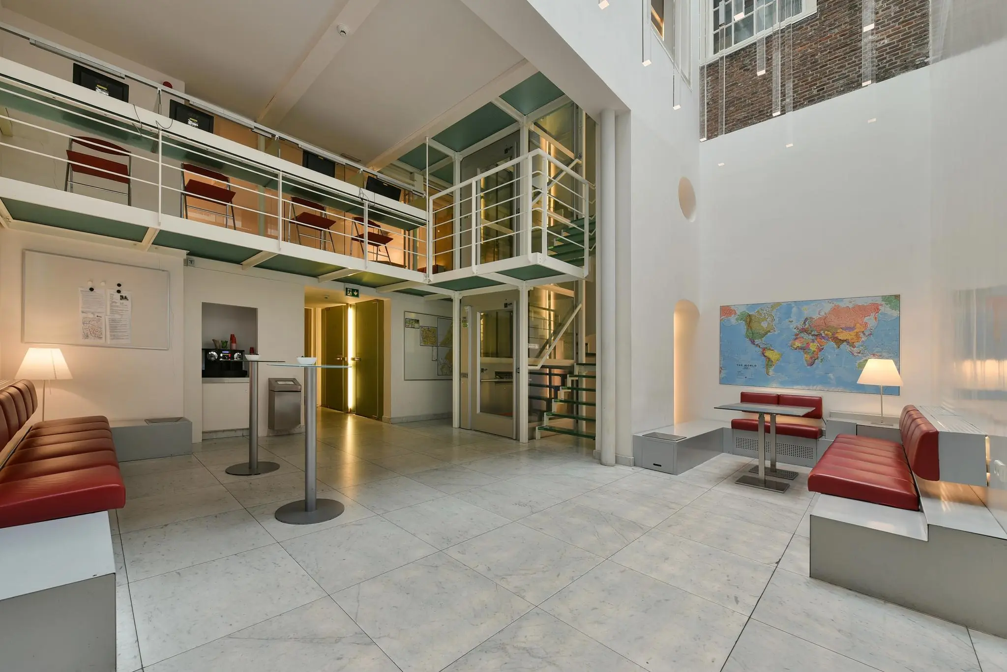 Moderne wachtruimte in het Rapenburg-gebouw met rode zitbanken, wereldkaart aan de muur en een open verdieping met werkplekken.