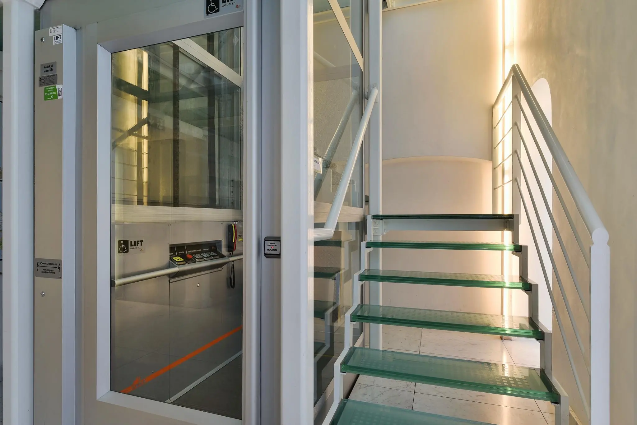 Moderne glazen trap en lift voor rolstoelgebruikers in gebouw aan het Rapenburg.