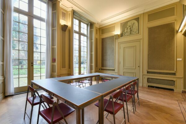 Vergaderzaal met een U-vormige tafelopstelling en hoge ramen in een klassiek pand aan het Rapenburg.