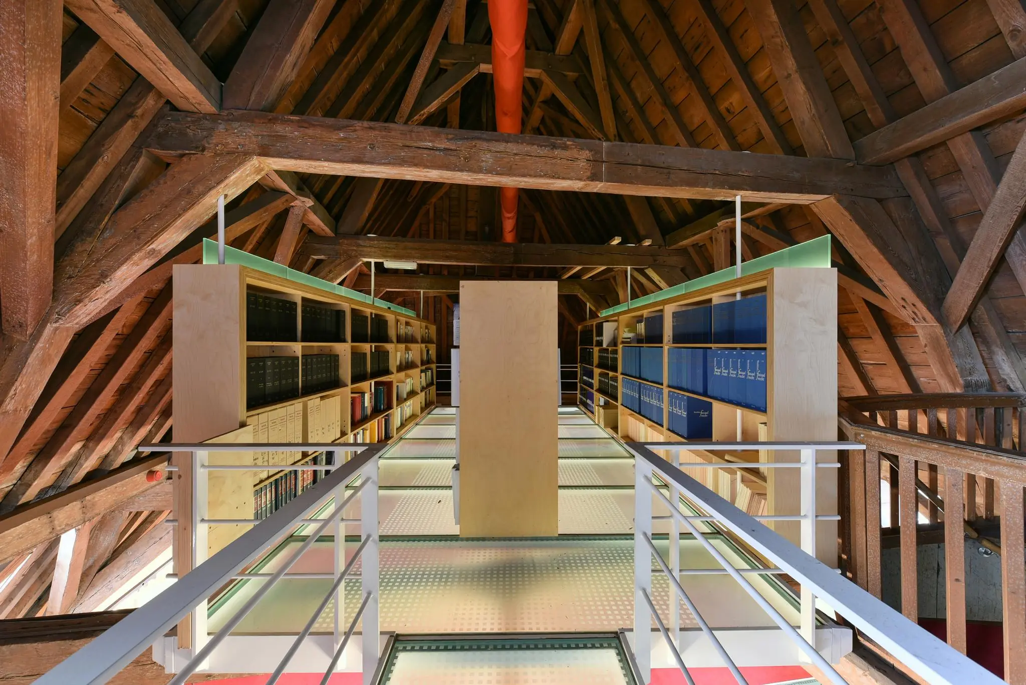 Een moderne bibliotheekruimte met houten balken en boekenrekken onder het dak van een historisch pand aan het Rapenburg.
