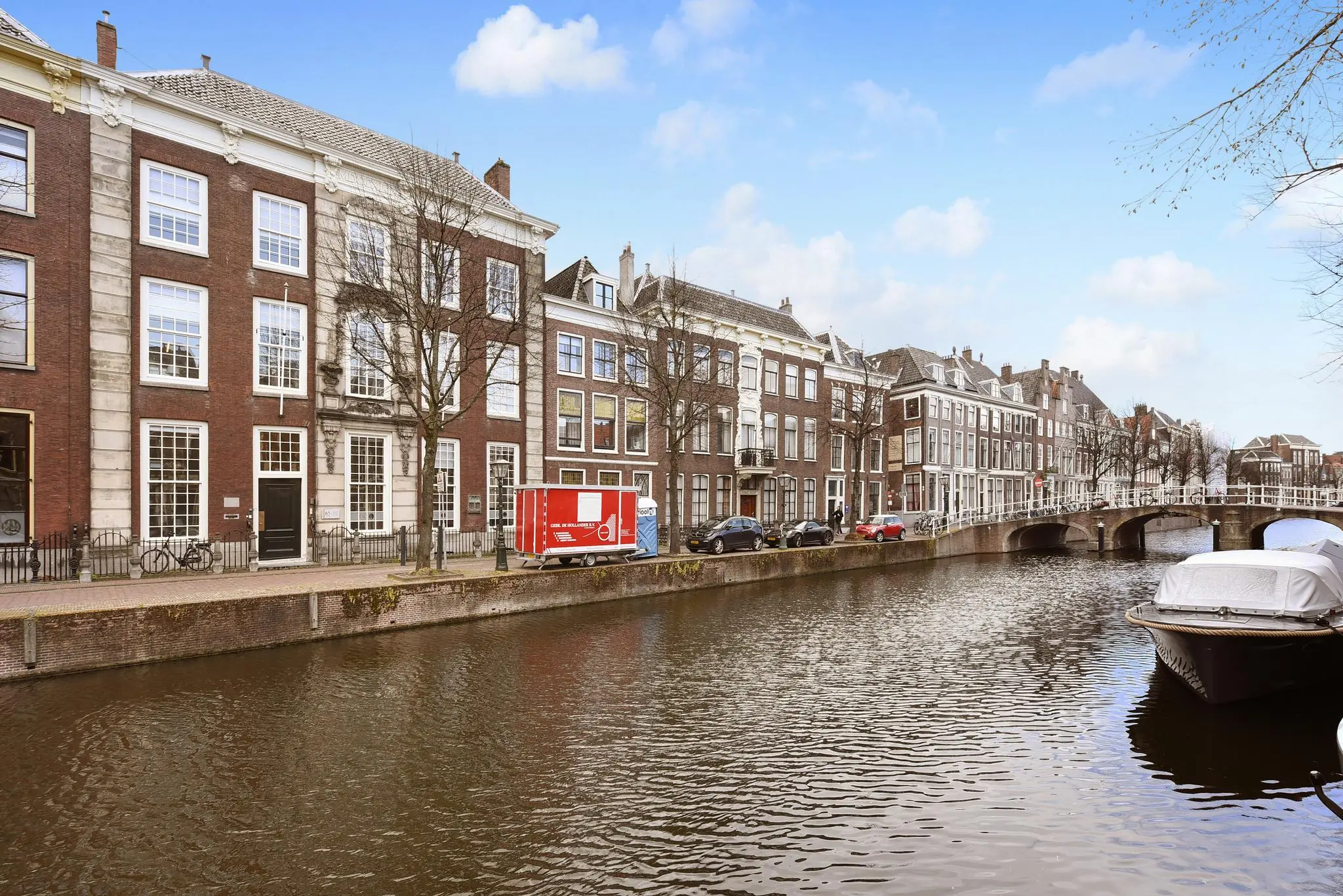 Historische gevels aan het Rapenburg in Leiden, langs een gracht met brug en aangemeerde boot.