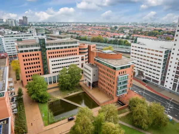 Luchtfoto van het Maanplein in Den Haag met kantoorgebouwen, een vijver en omliggende woonwijken.