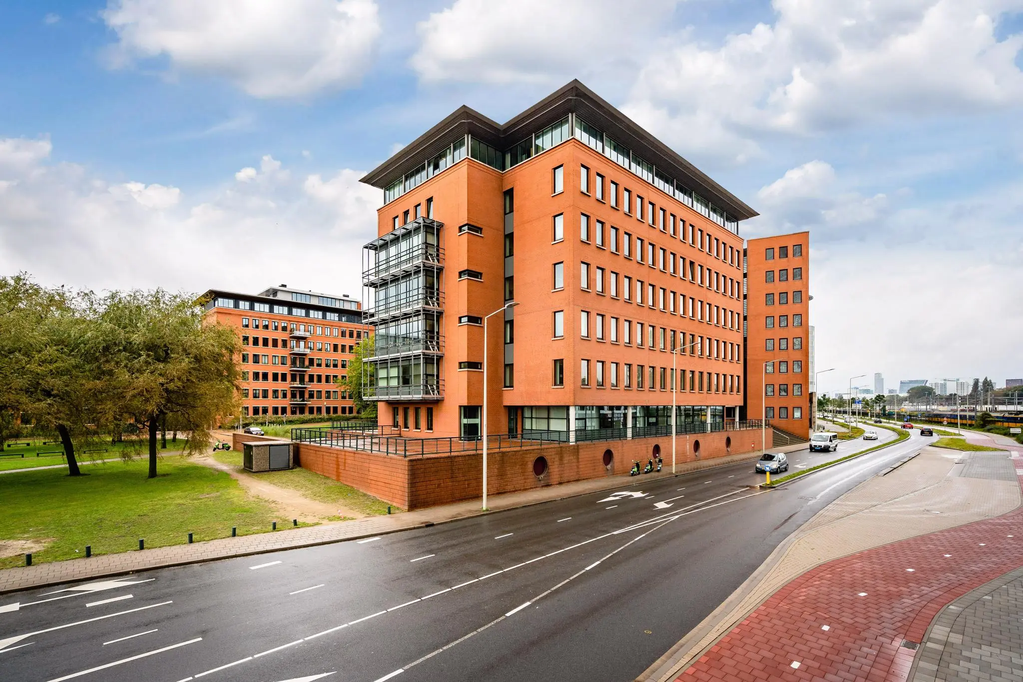 Modern kantoorgebouw aan het Maanplein in Den Haag naast een brede weg en groenstrook.