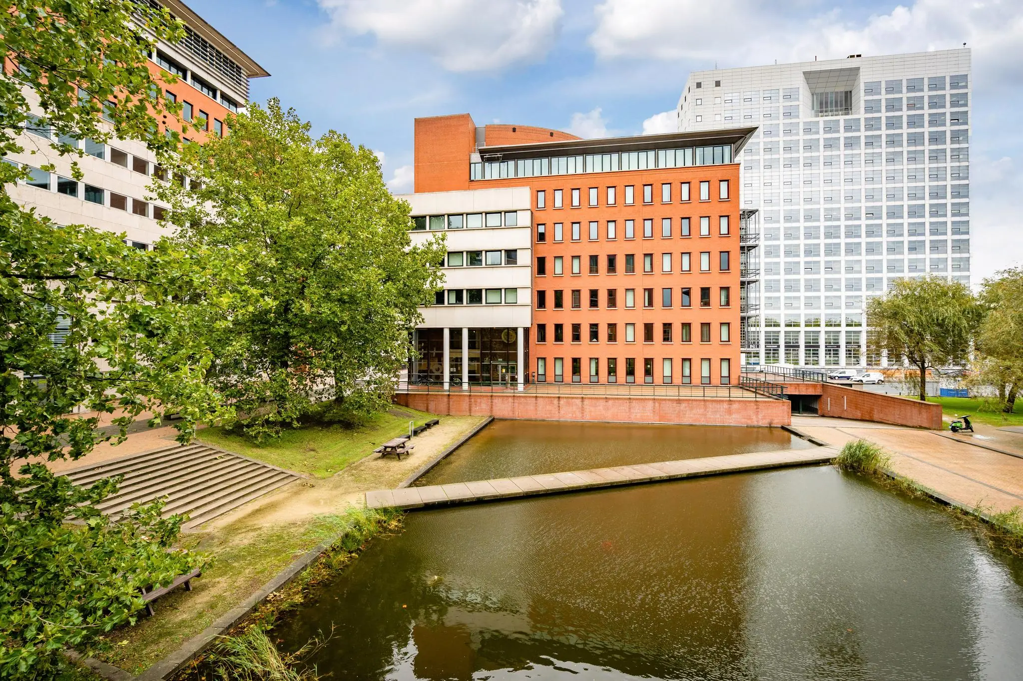 Kantoorgebouwen aan het Maanplein in Den Haag met vijver en wandelpad op de voorgrond.