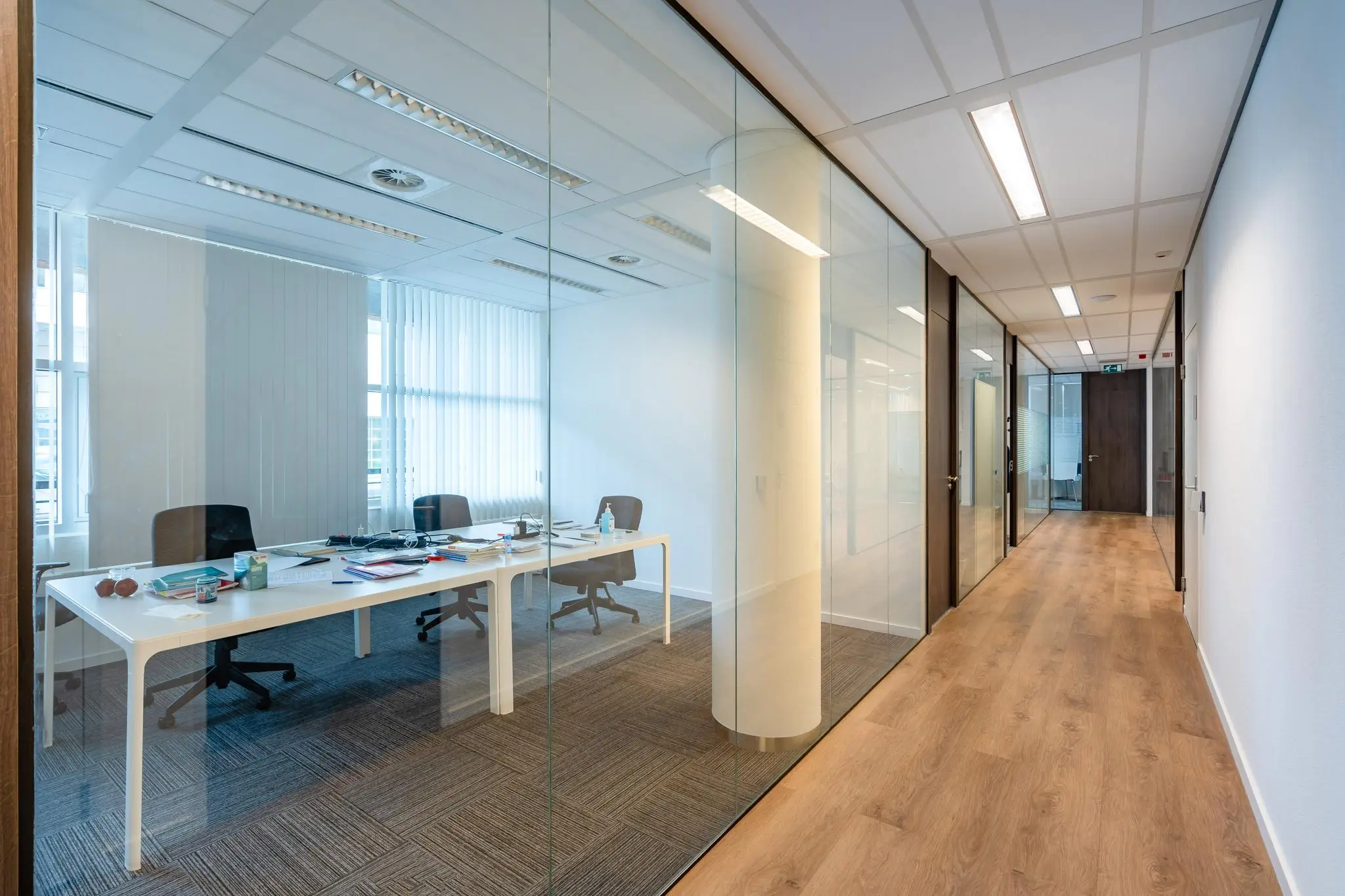 Moderne kantoorruimte aan het Maanplein met glazen wanden, houten vloer en een vergaderruimte zichtbaar aan de linkerkant.