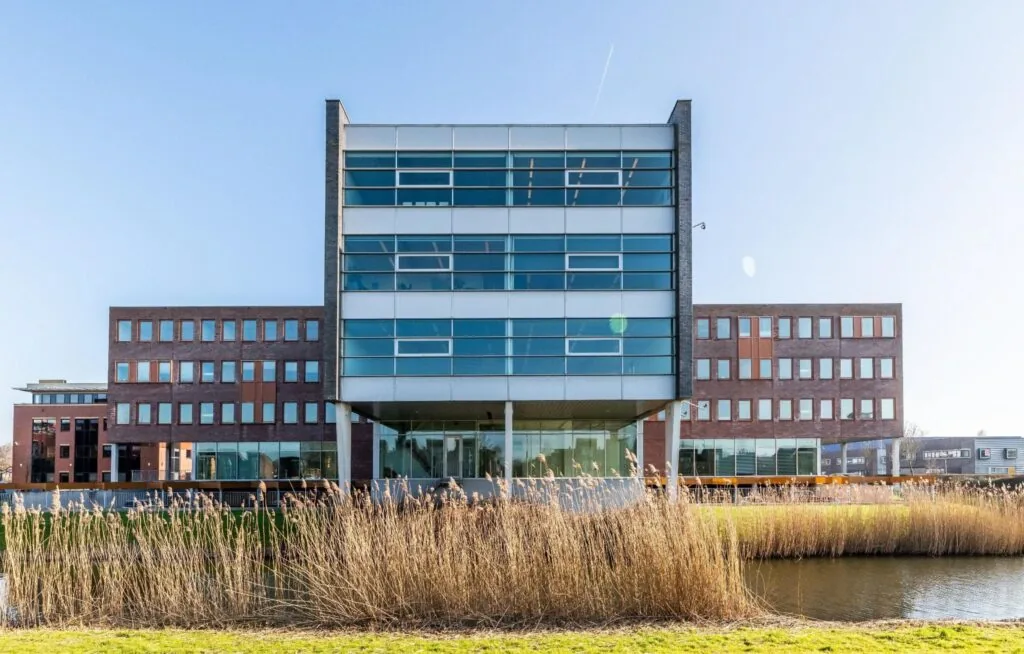 Modern kantoorgebouw Trondheim met glazen gevel en waterpartij op de voorgrond.