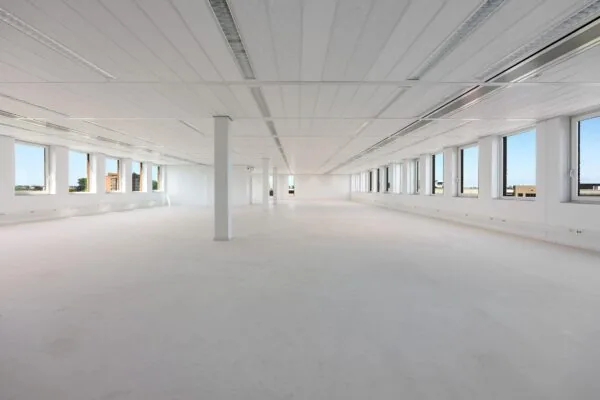 Lichte, ruime en lege kantoorruimte met grote ramen in een modern gebouw in Trondheim.