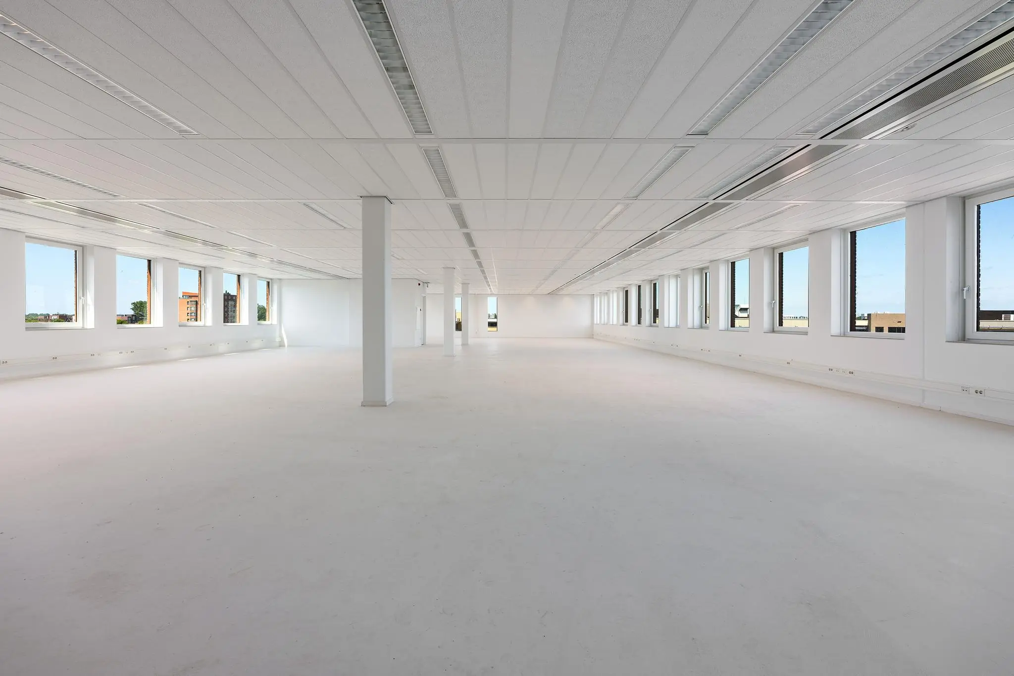 Lichte, ruime en lege kantoorruimte met grote ramen in een modern gebouw in Trondheim.