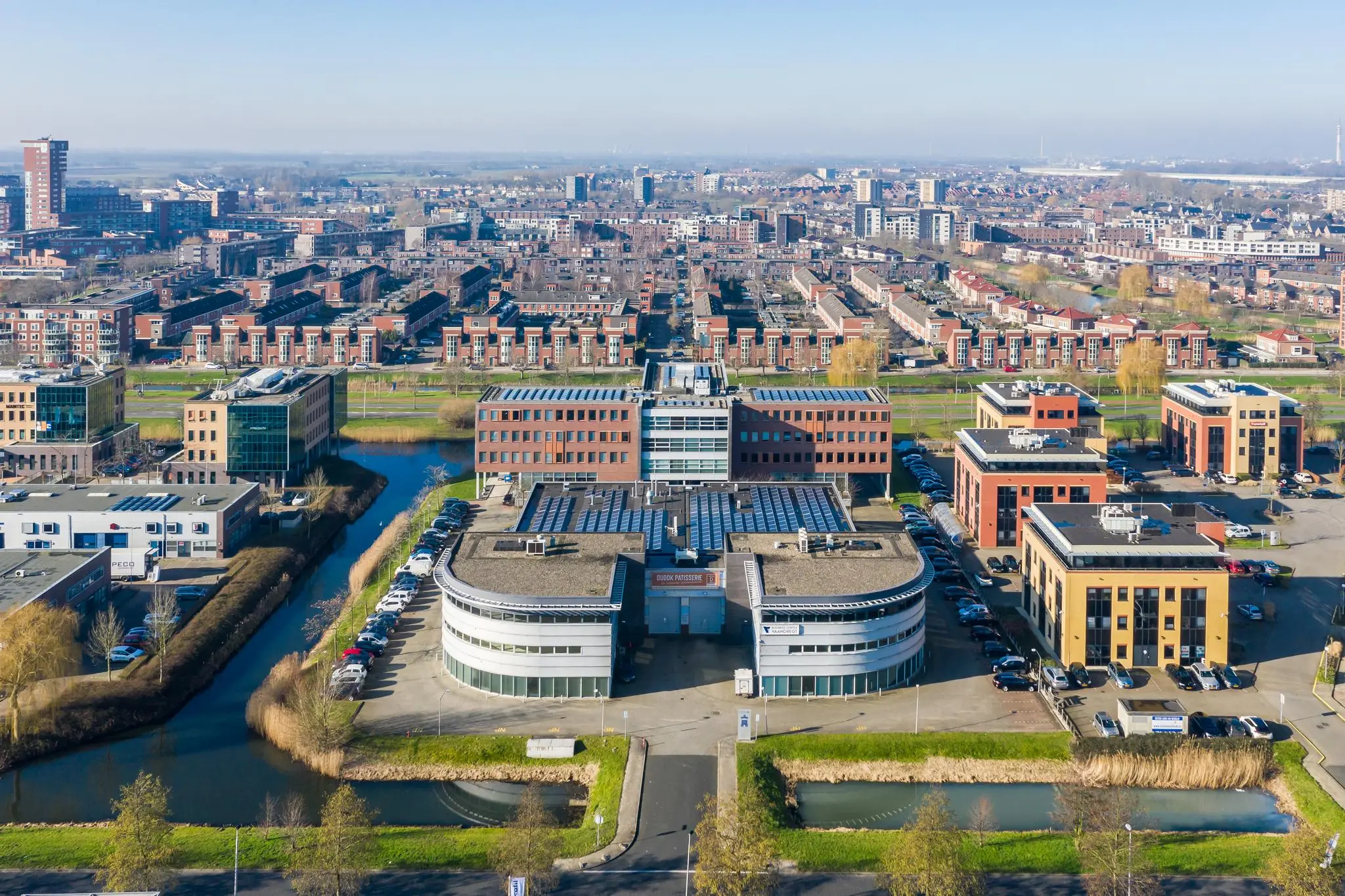 Luchtfoto van het Trondheim bedrijvenpark in Groningen met moderne kantoorgebouwen en woonwijken op de achtergrond.