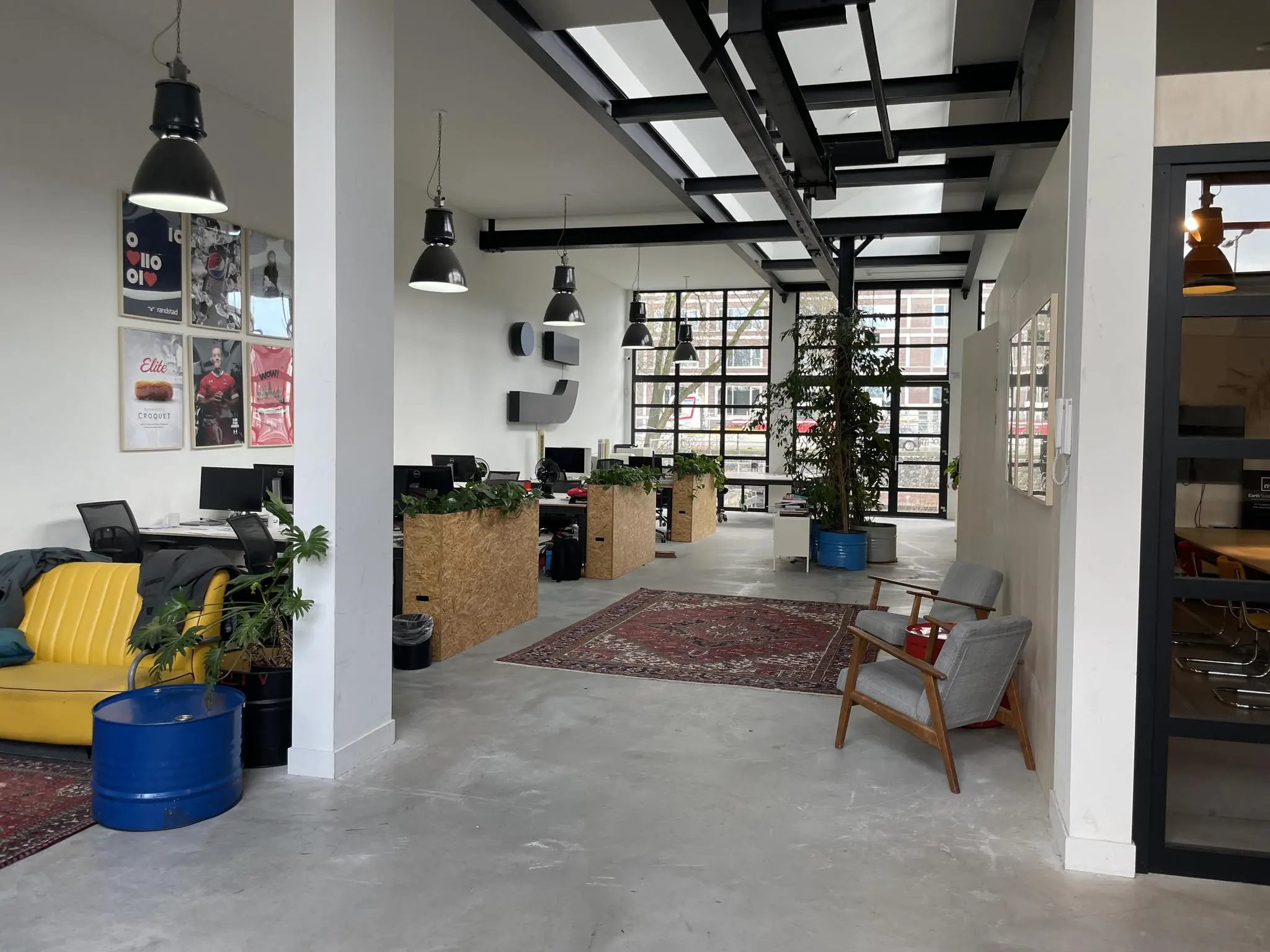 Moderne, open kantoorruimte in het Veemarktgebouw met industriële inrichting, bureaus, planten en zithoeken.