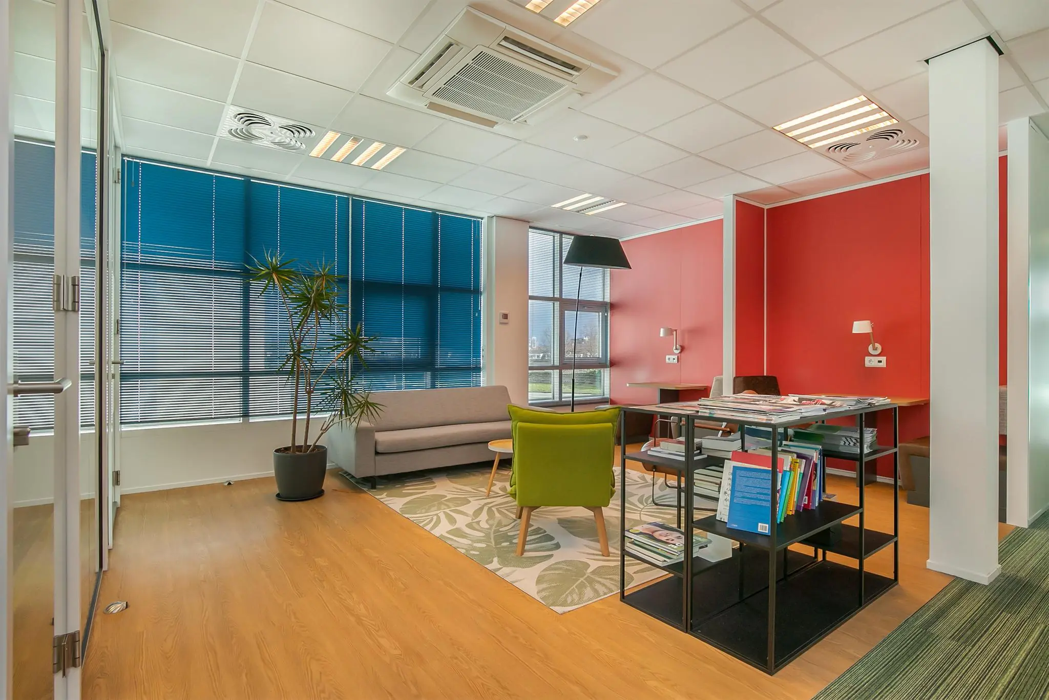 Modern ingerichte wachtruimte in kantoorpand Rhijnspoor met kleurrijke meubels, planten en tijdschriftenrek.