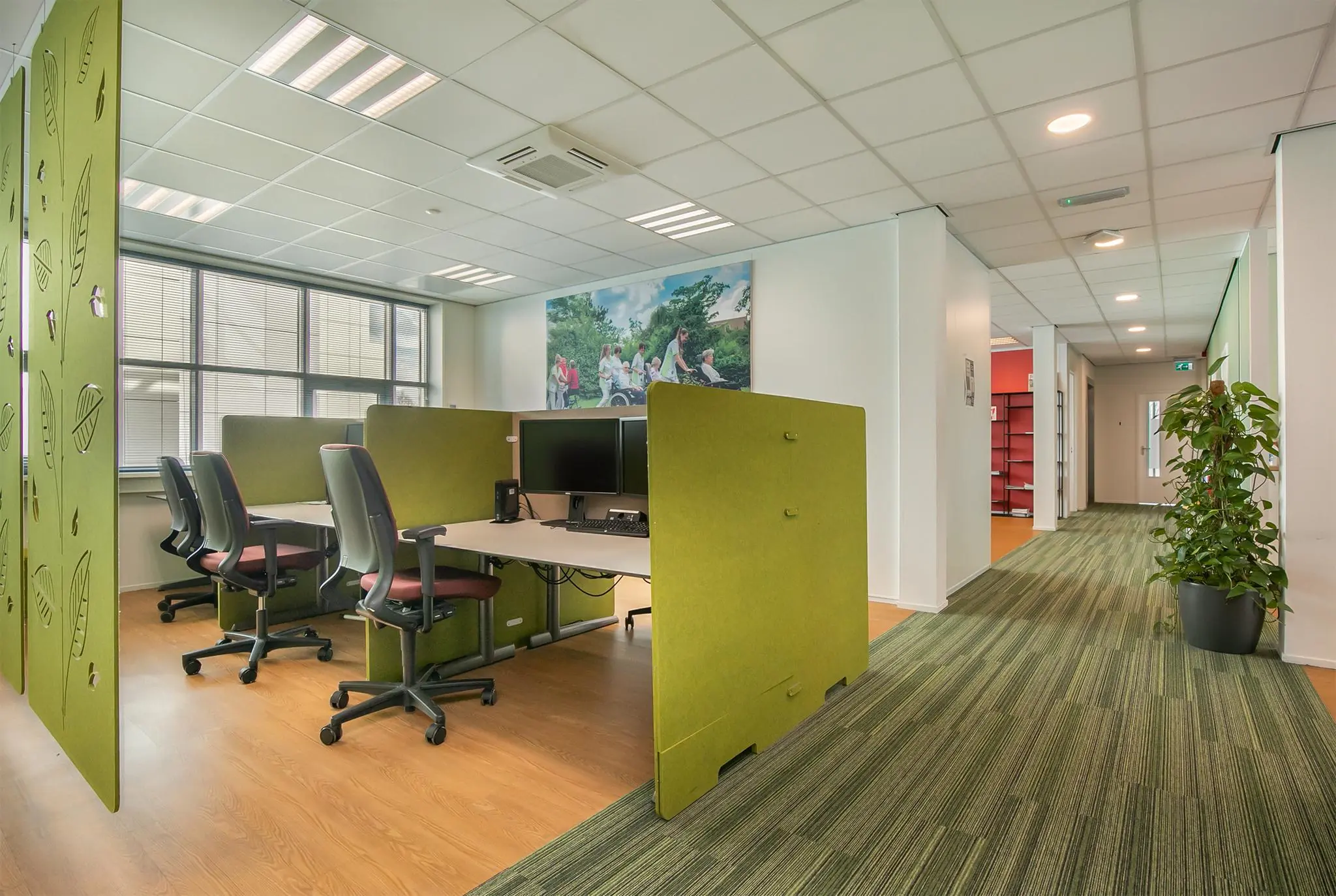 Modern kantoorinterieur met groene akoestische werkplekken en een frisse, open gang bij Rhijnspoor.