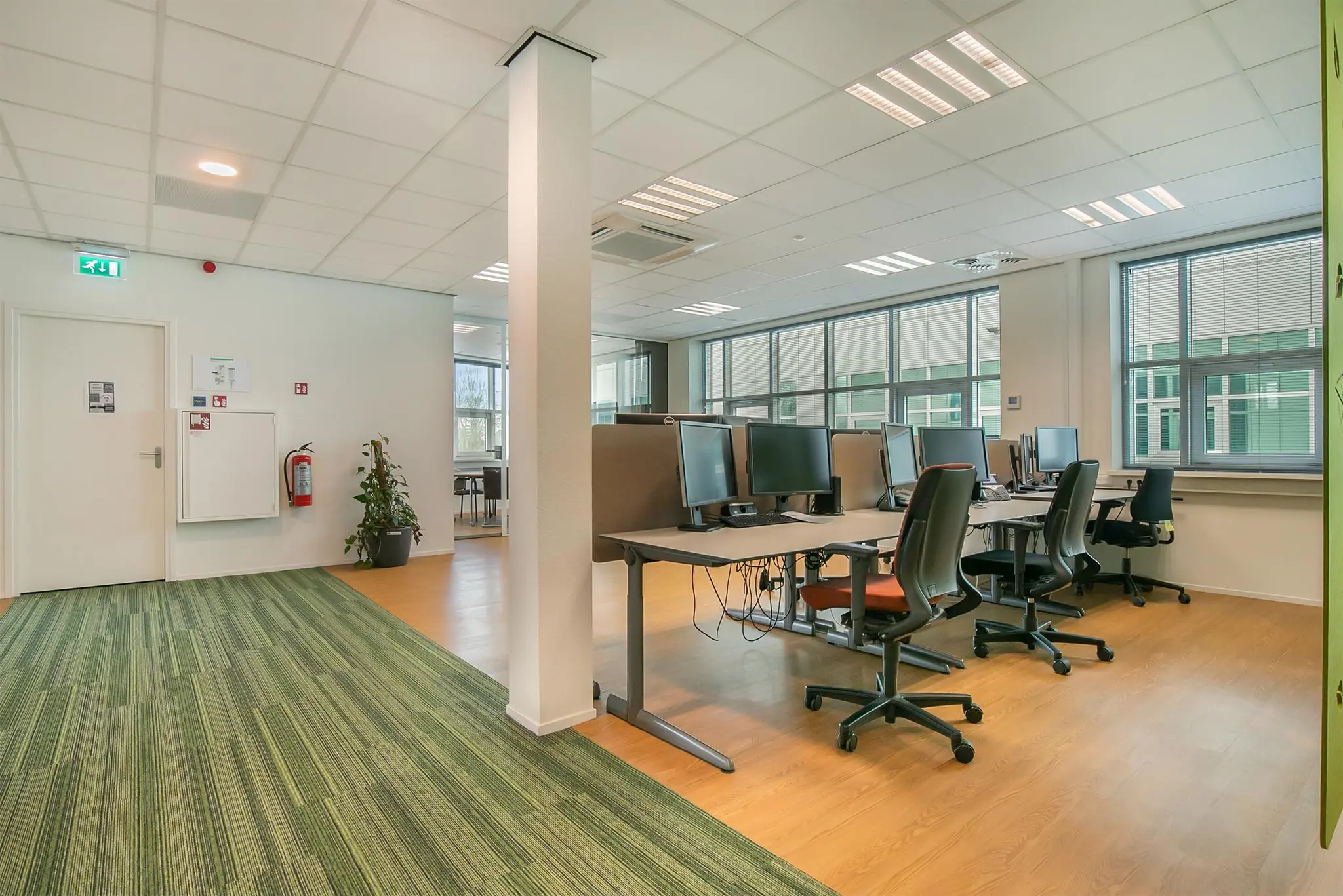Moderne kantoorruimte aan het Rhijnspoor met werkplekken, bureaustoelen en grote ramen voor natuurlijke lichtinval.