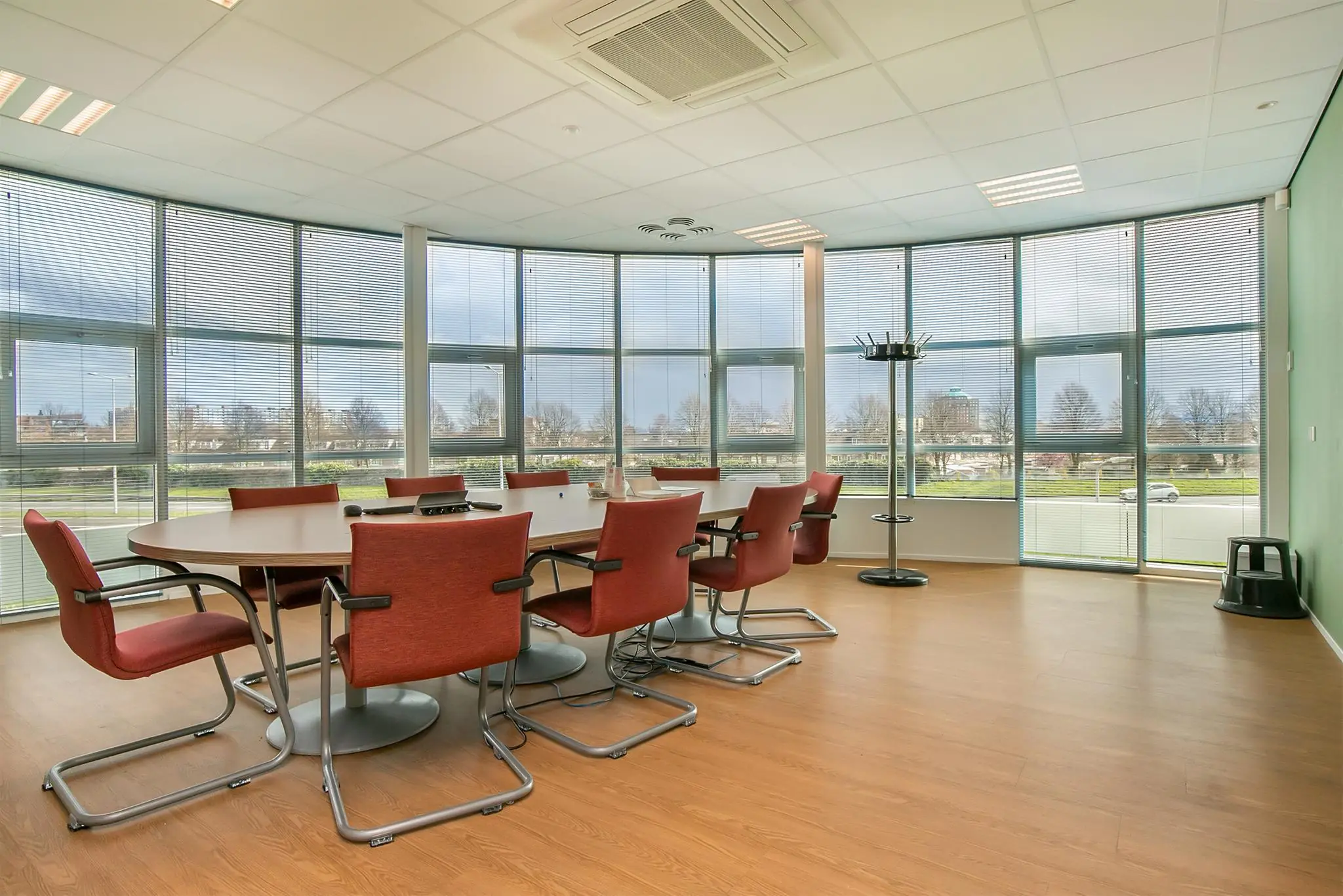 Vergaderruimte met ovale tafel, rode stoelen en panoramisch uitzicht op het Rhijnspoor.