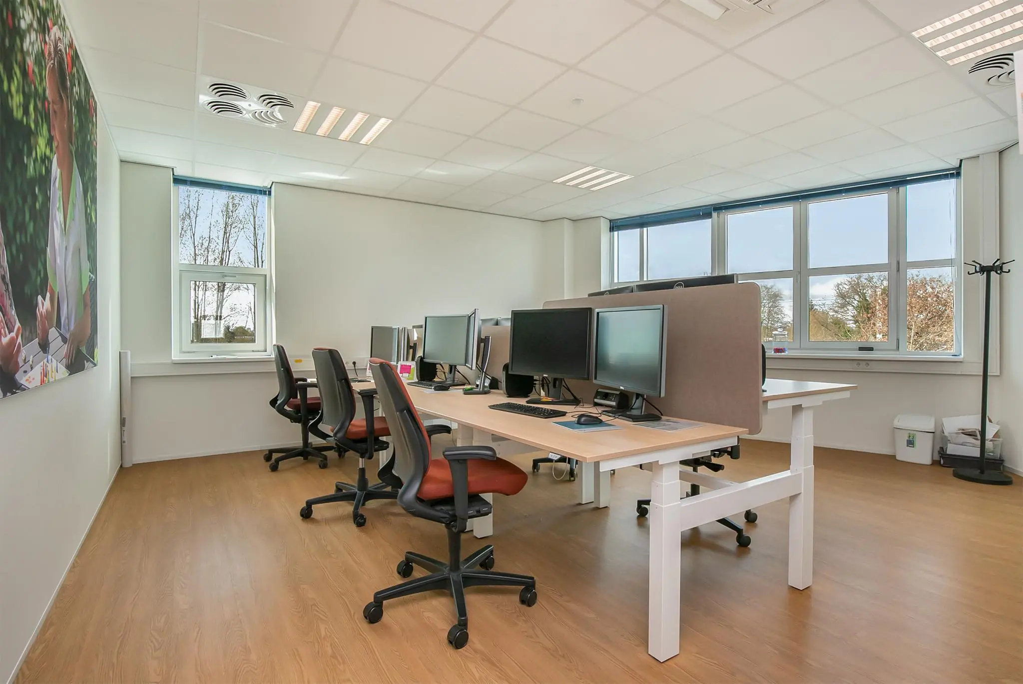 Moderne en lichte kantoorruimte in het Rhijnspoor-gebouw met meerdere werkplekken en grote ramen.