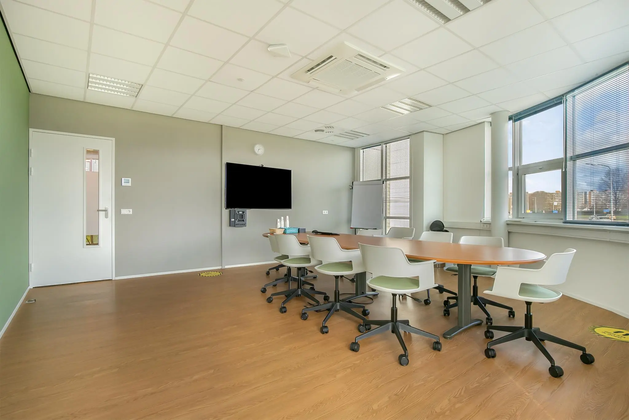 Moderne vergaderruimte in het Rhijnspoor-gebouw met ovale tafel, bureaustoelen, flatscreen en whiteboard.