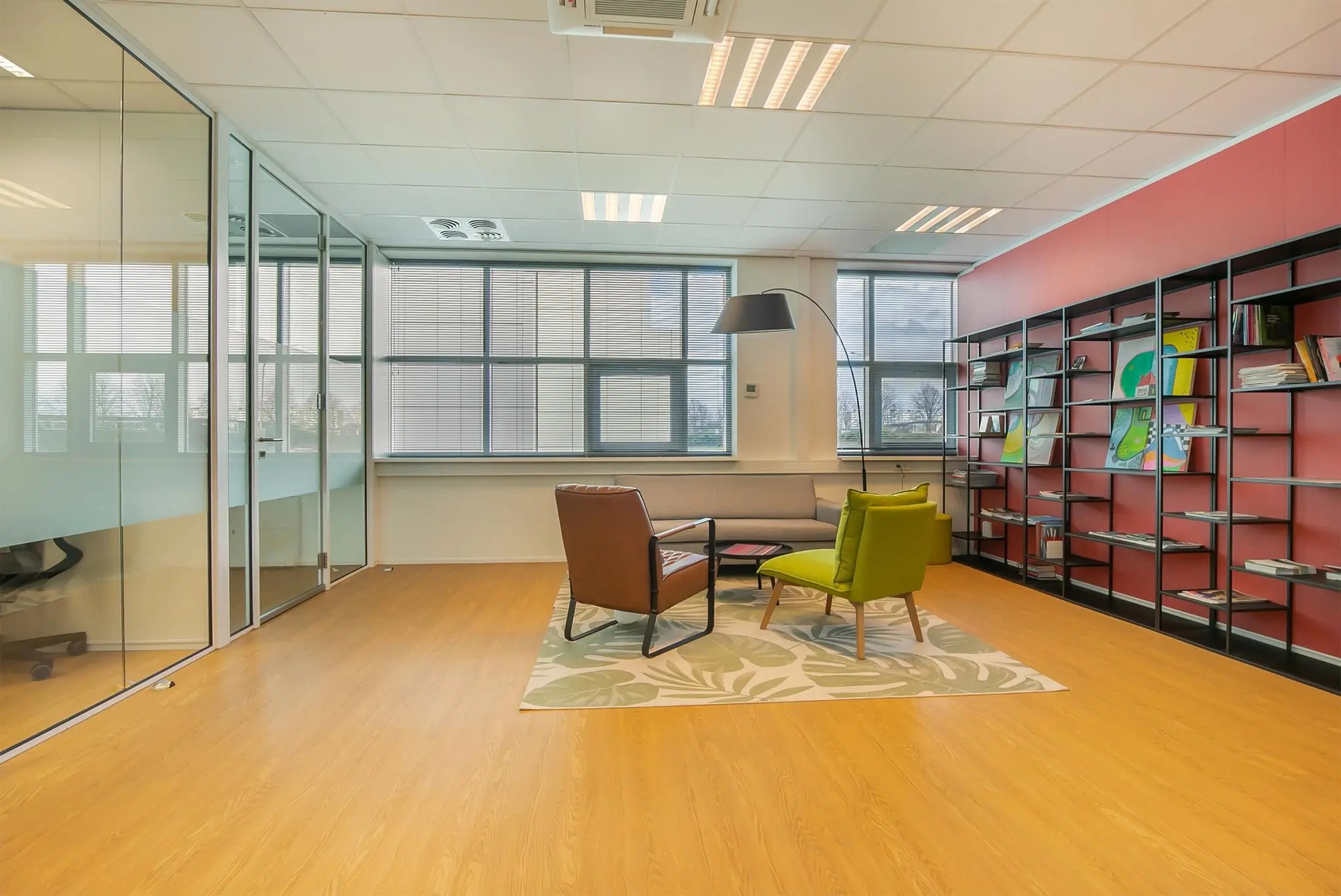 Moderne kantoorruimte aan het Rhijnspoor met zithoek, boekenkast en grote ramen.