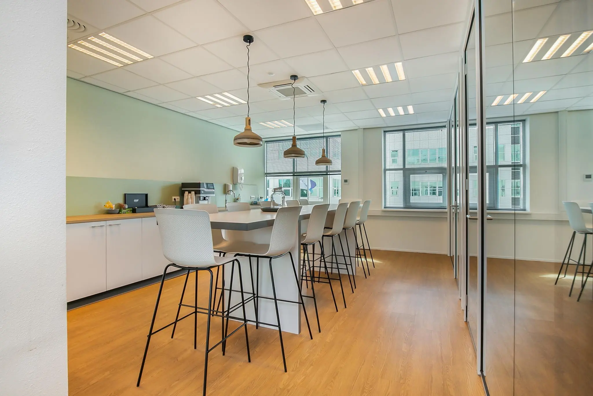 Moderne kantoor kantine met hoge stoelen, hanglampen en een lange tafel in het Rhijnspoor-gebouw.
